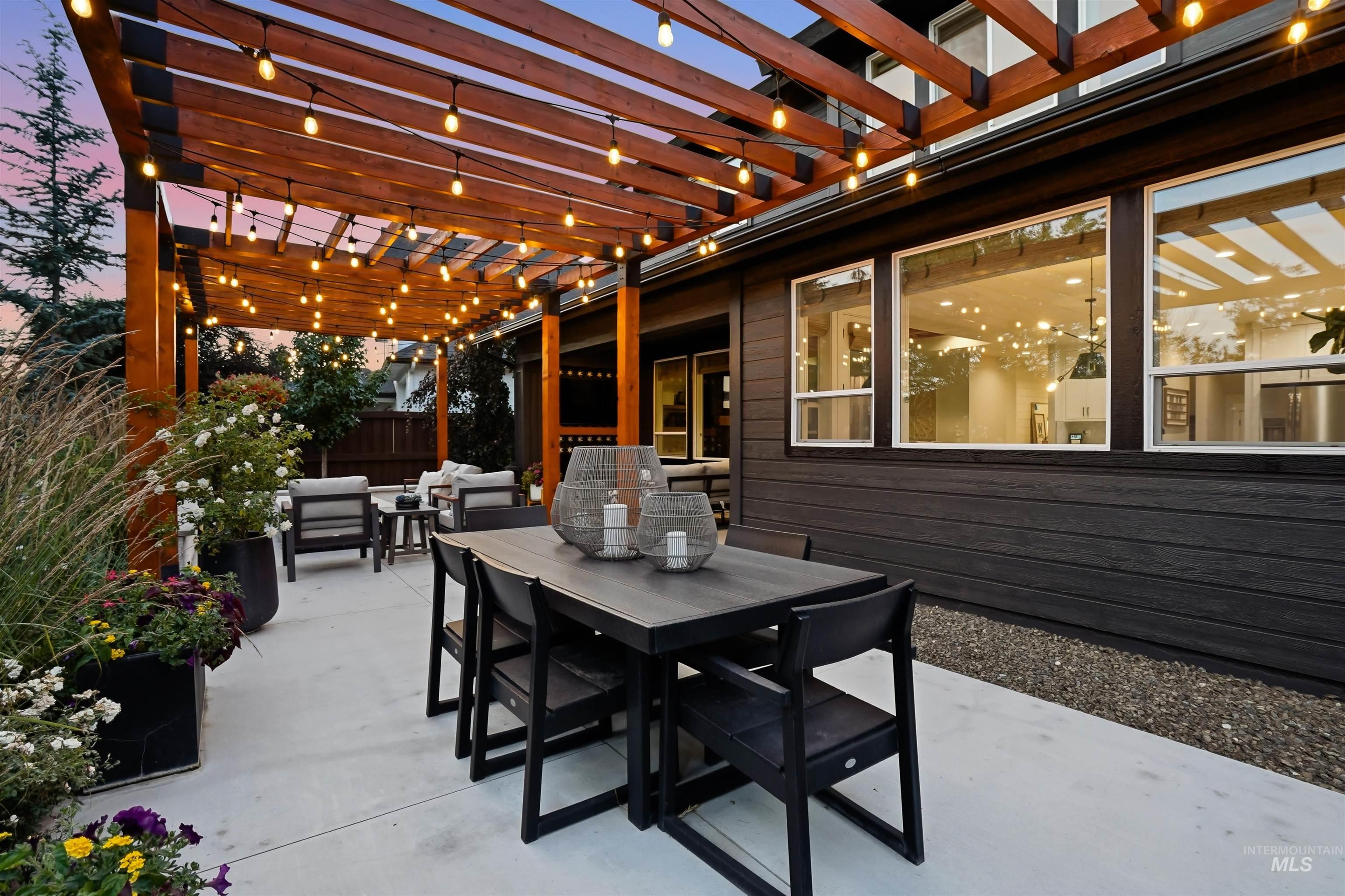 Expansive concrete patio featuring a wooden pergola with string lighting