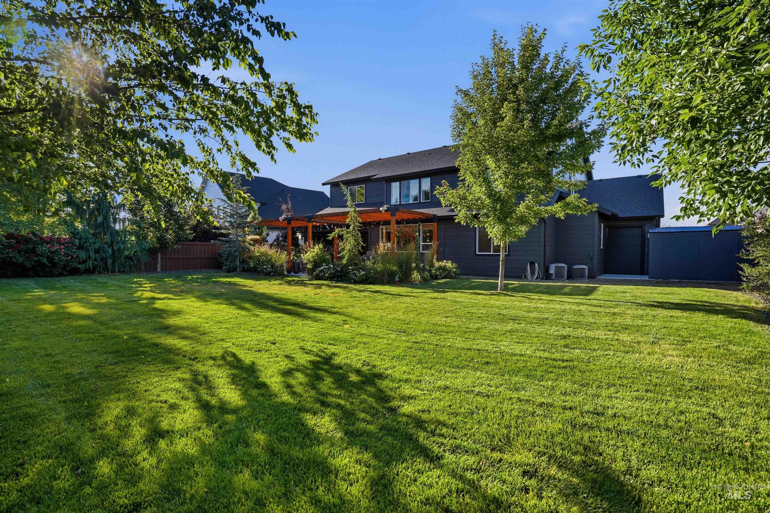 Expansive green lawn with mature trees and a dark-toned residence