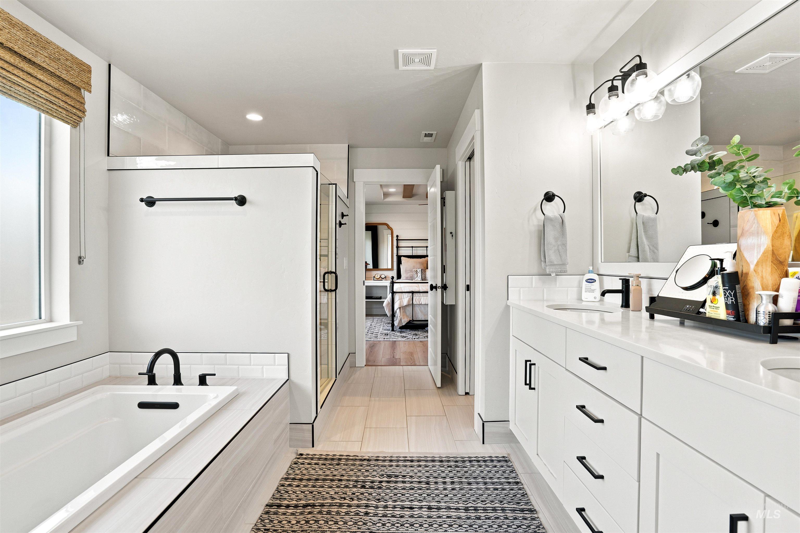 Contemporary bathroom featuring a built-in soaking tub with matte black fixtures, a walk-in shower with clear glass enclosure, and a double vanity with ample storage