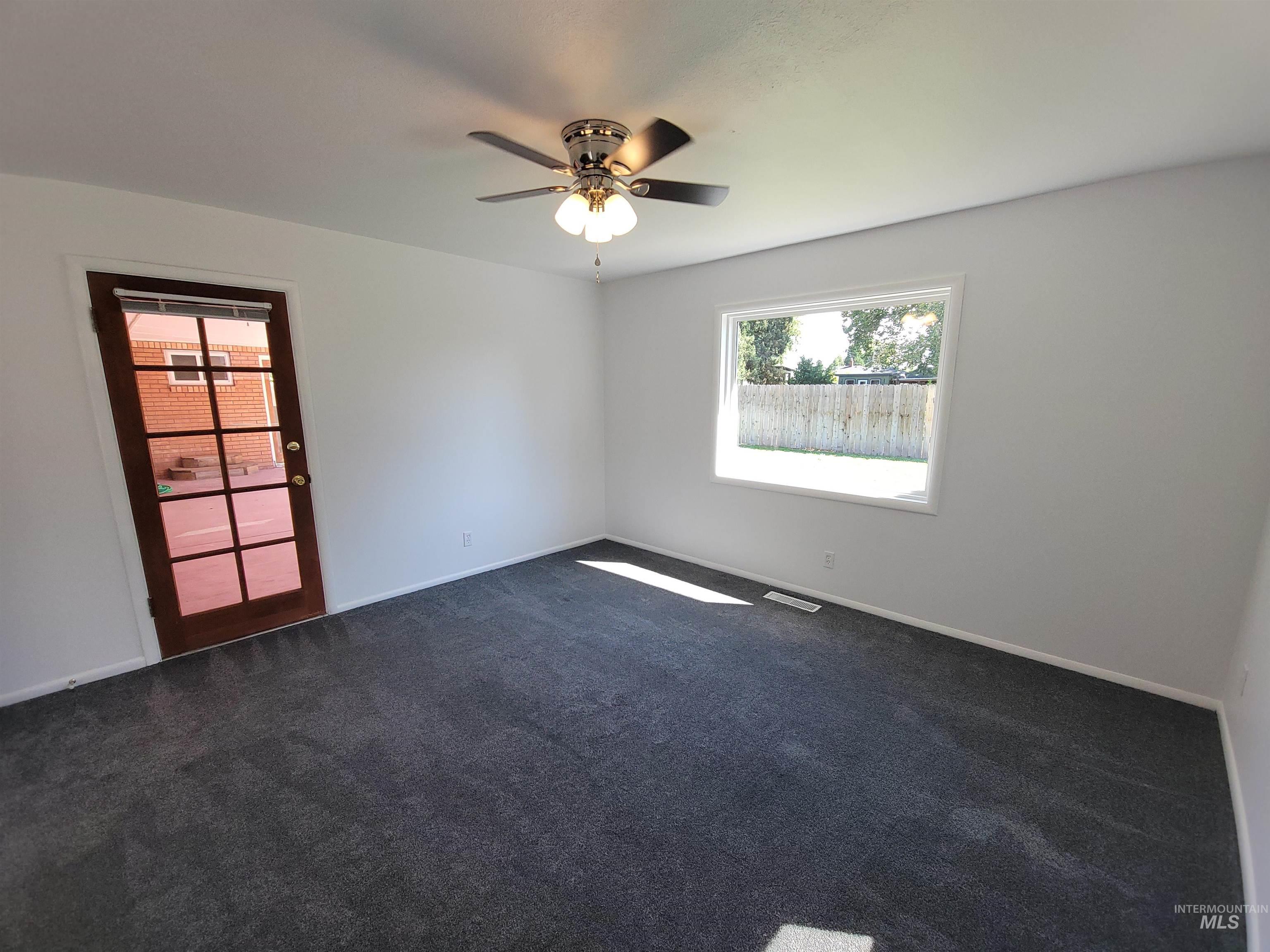 Spare room featuring dark carpet and ceiling fan