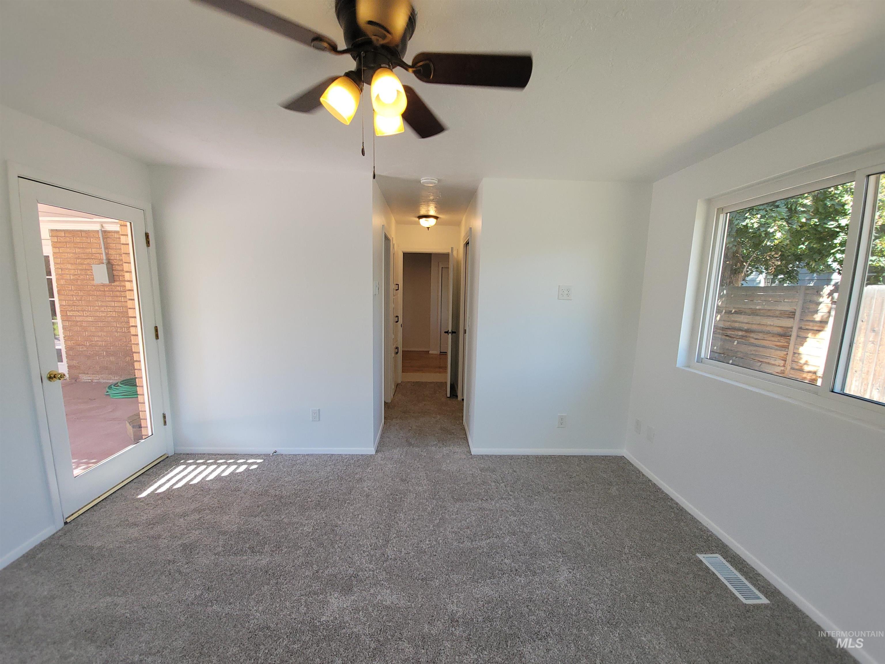 Unfurnished bedroom featuring carpet flooring, access to exterior, and a ceiling fan