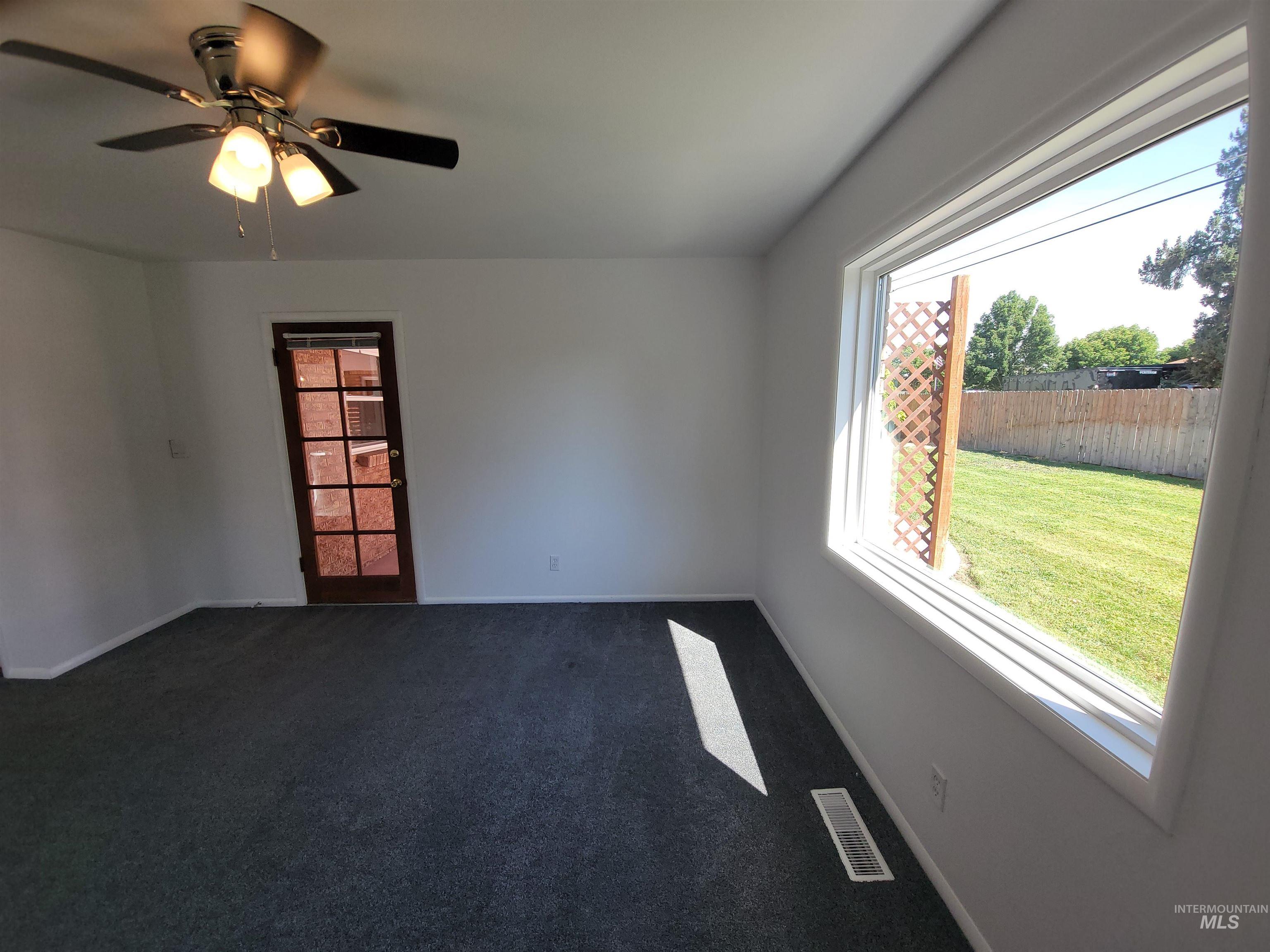 Unfurnished room with dark colored carpet and a ceiling fan