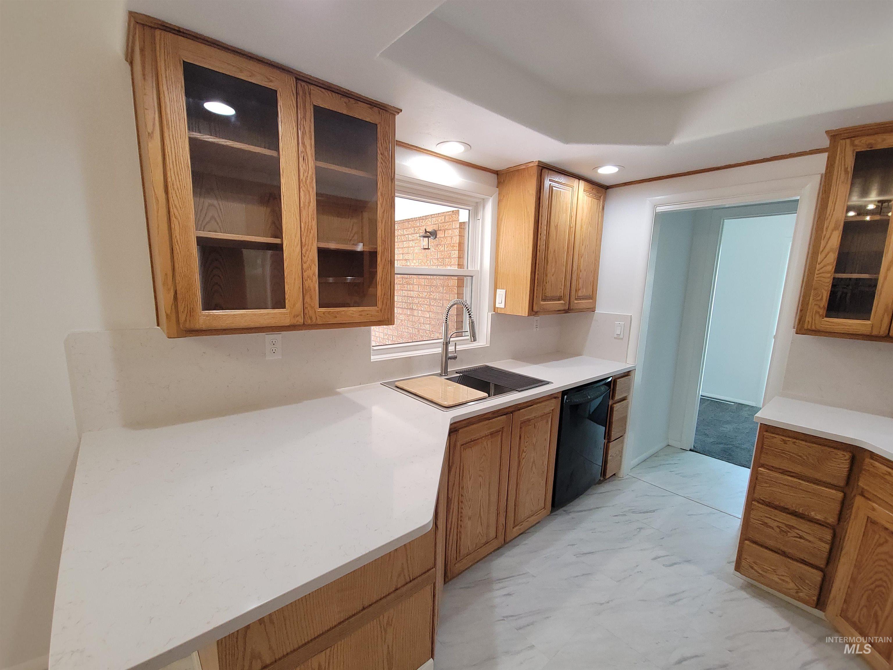Kitchen featuring glass insert cabinets, light marble finish floors, brown cabinets, dishwasher, and recessed lighting
