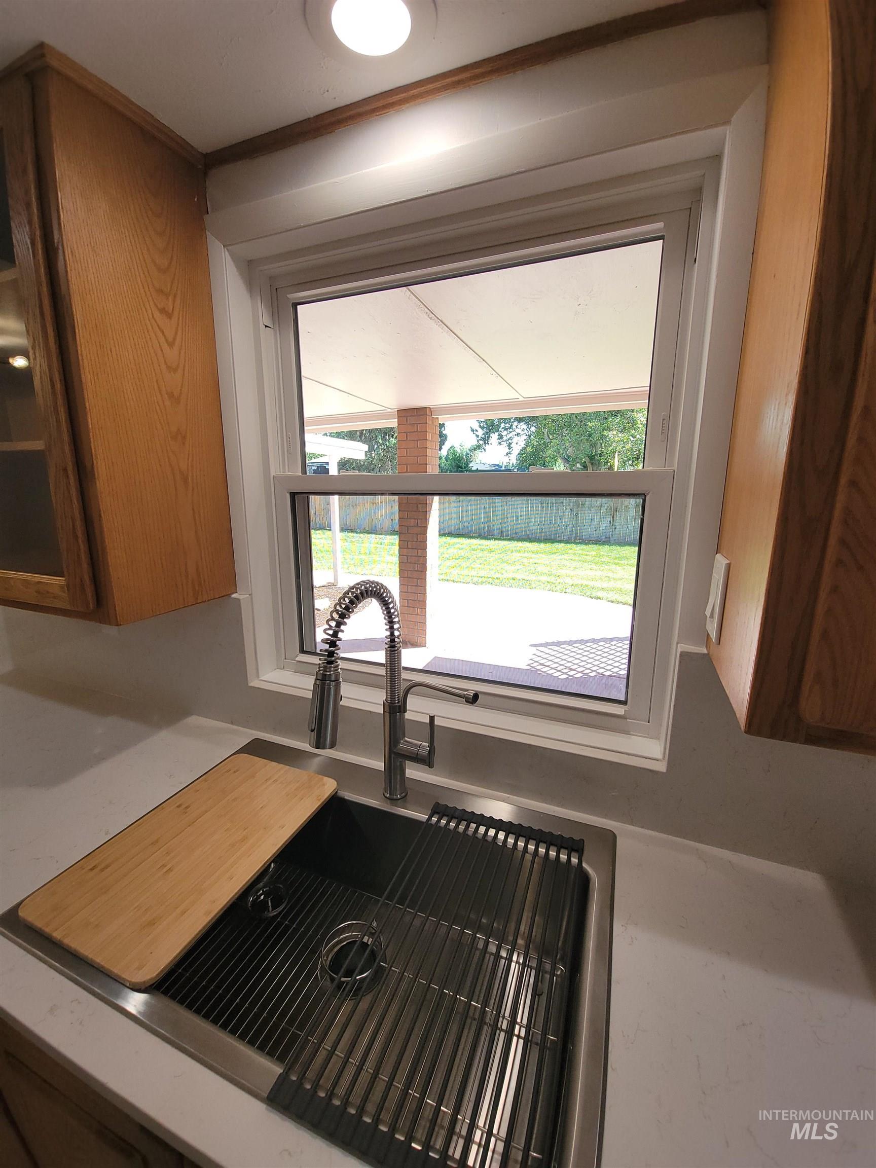 Kitchen view of brown cabinets and light stone countertops