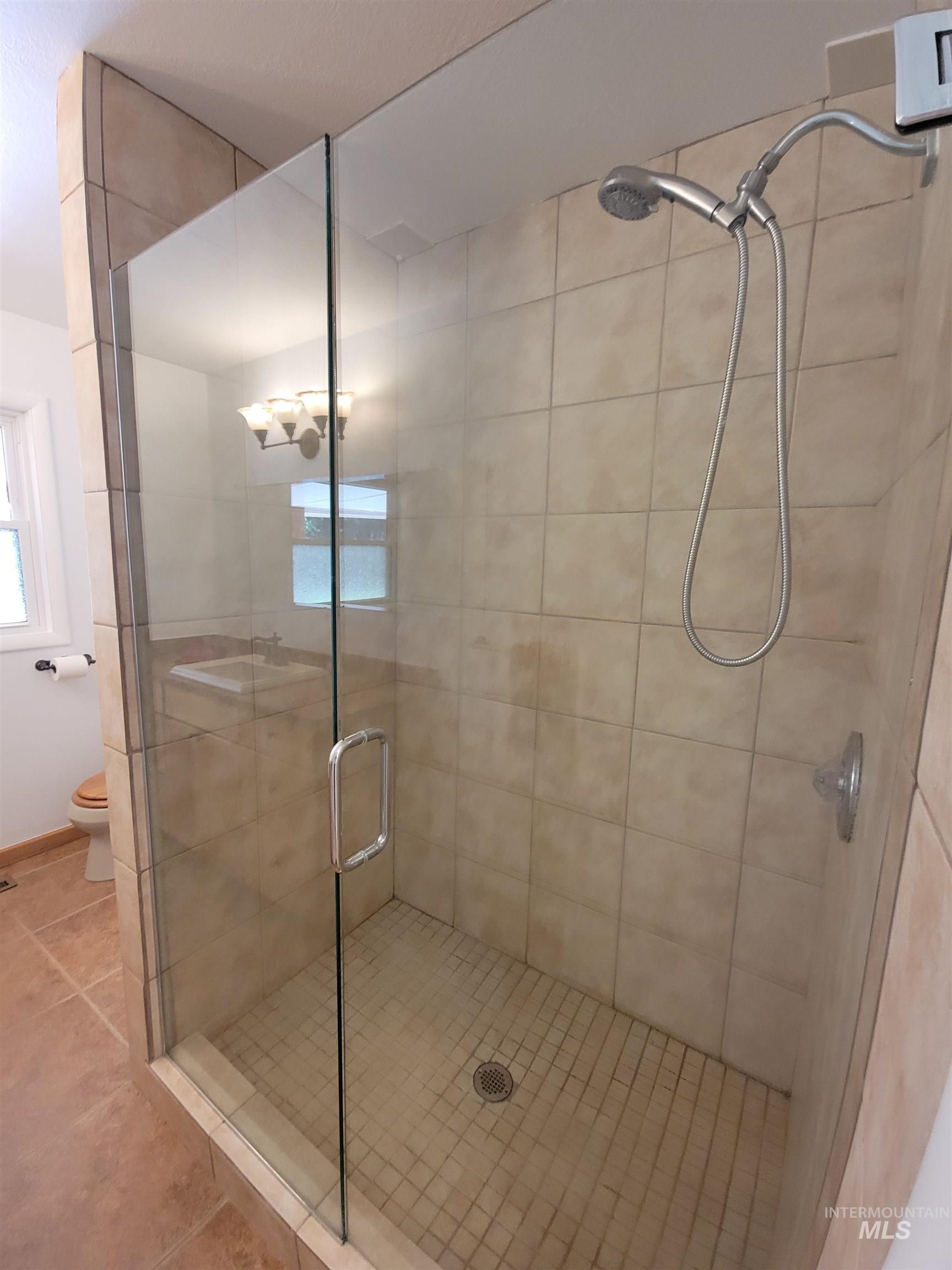 Full bathroom with a stall shower and tile patterned flooring