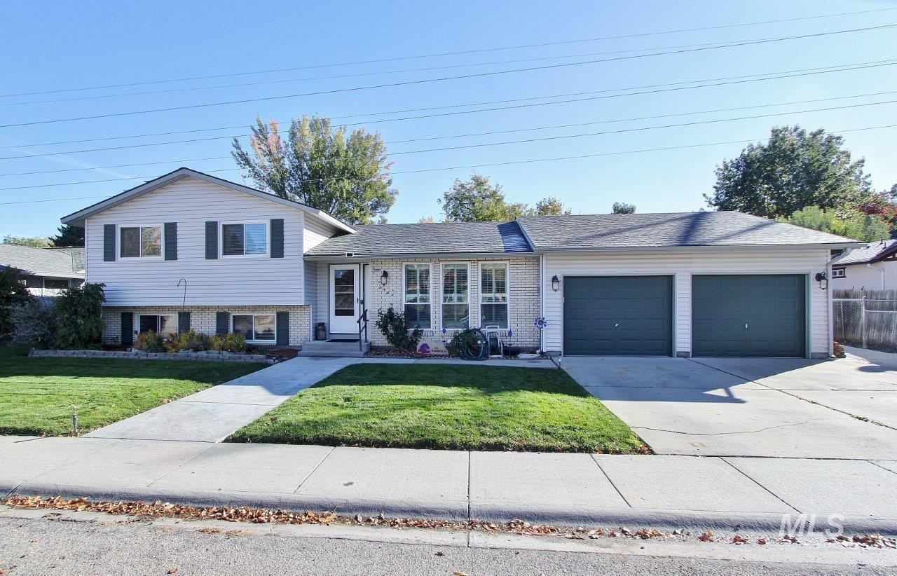 Split level home featuring brick siding, driveway, a garage, and a front lawn
