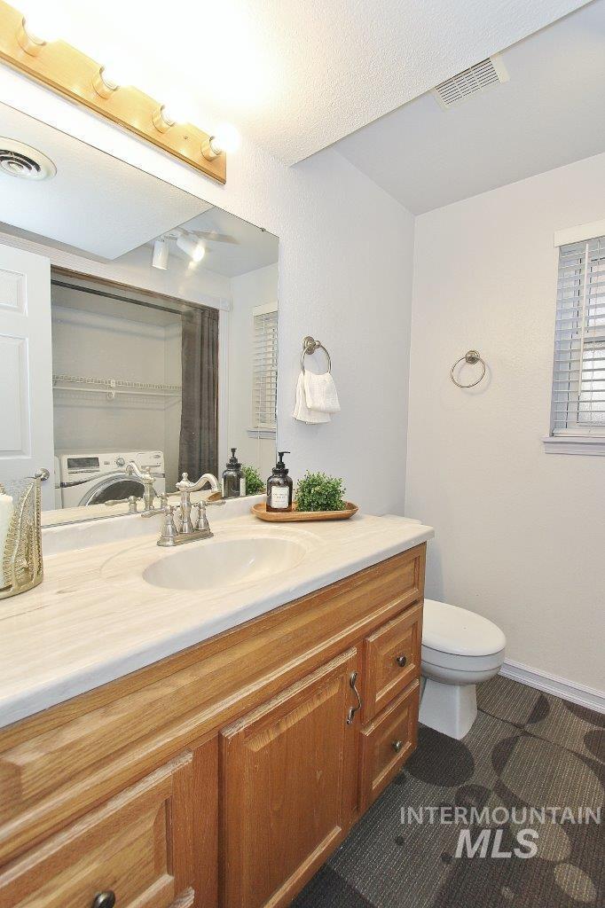 Bathroom with vanity, curtained shower, and washing machine and clothes dryer