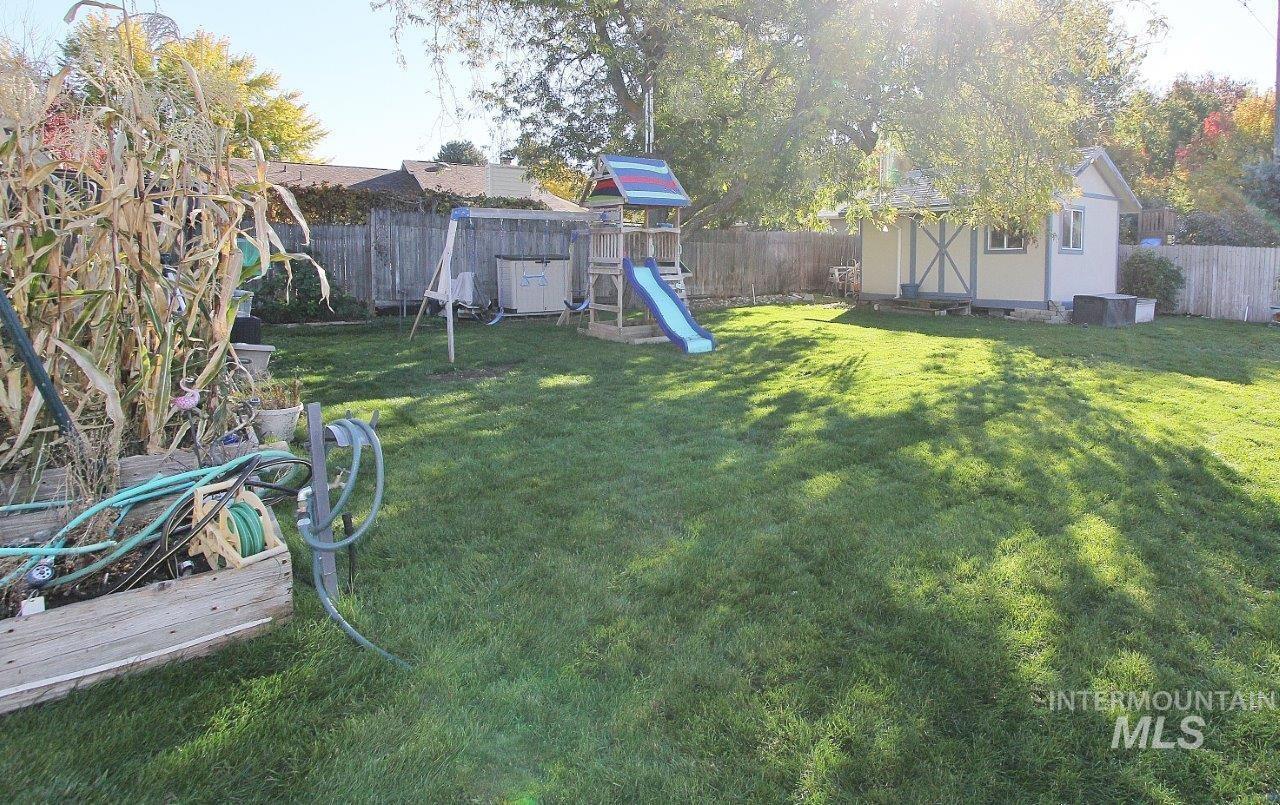 Fenced backyard with a playground and a shed