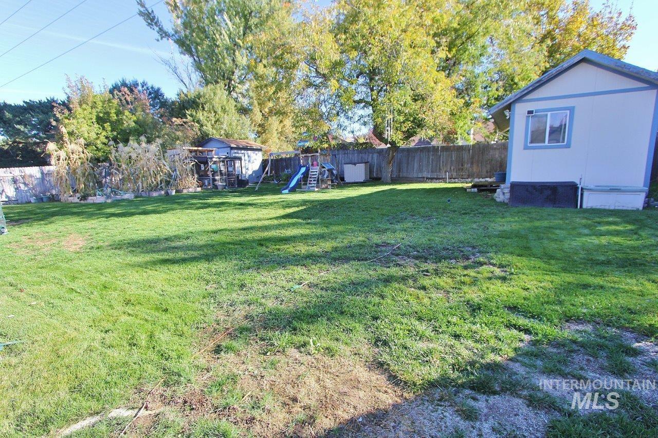 Fenced backyard with a playground and a storage unit
