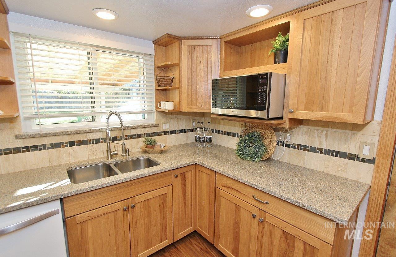 Kitchen featuring open shelves, light stone countertops, stainless steel microwave, backsplash, and recessed lighting