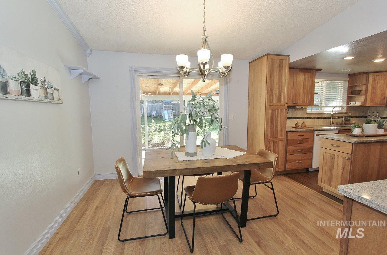 Dining room featuring light wood-style floors, a chandelier, and a textured ceiling
