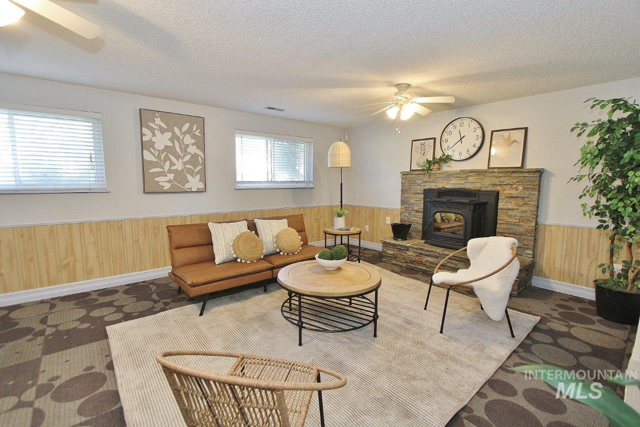Living room featuring ceiling fan, a wainscoted wall, wooden walls, and a textured ceiling