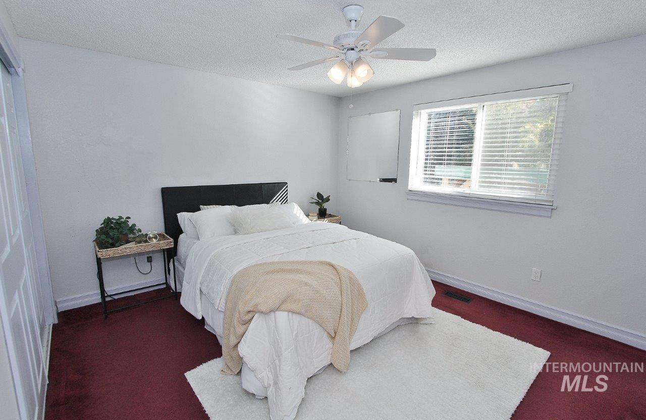 Bedroom featuring a textured ceiling, ceiling fan, and dark colored carpet