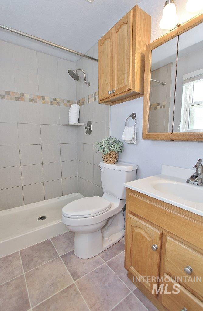 Full bath featuring a shower stall, vanity, and light tile patterned floors