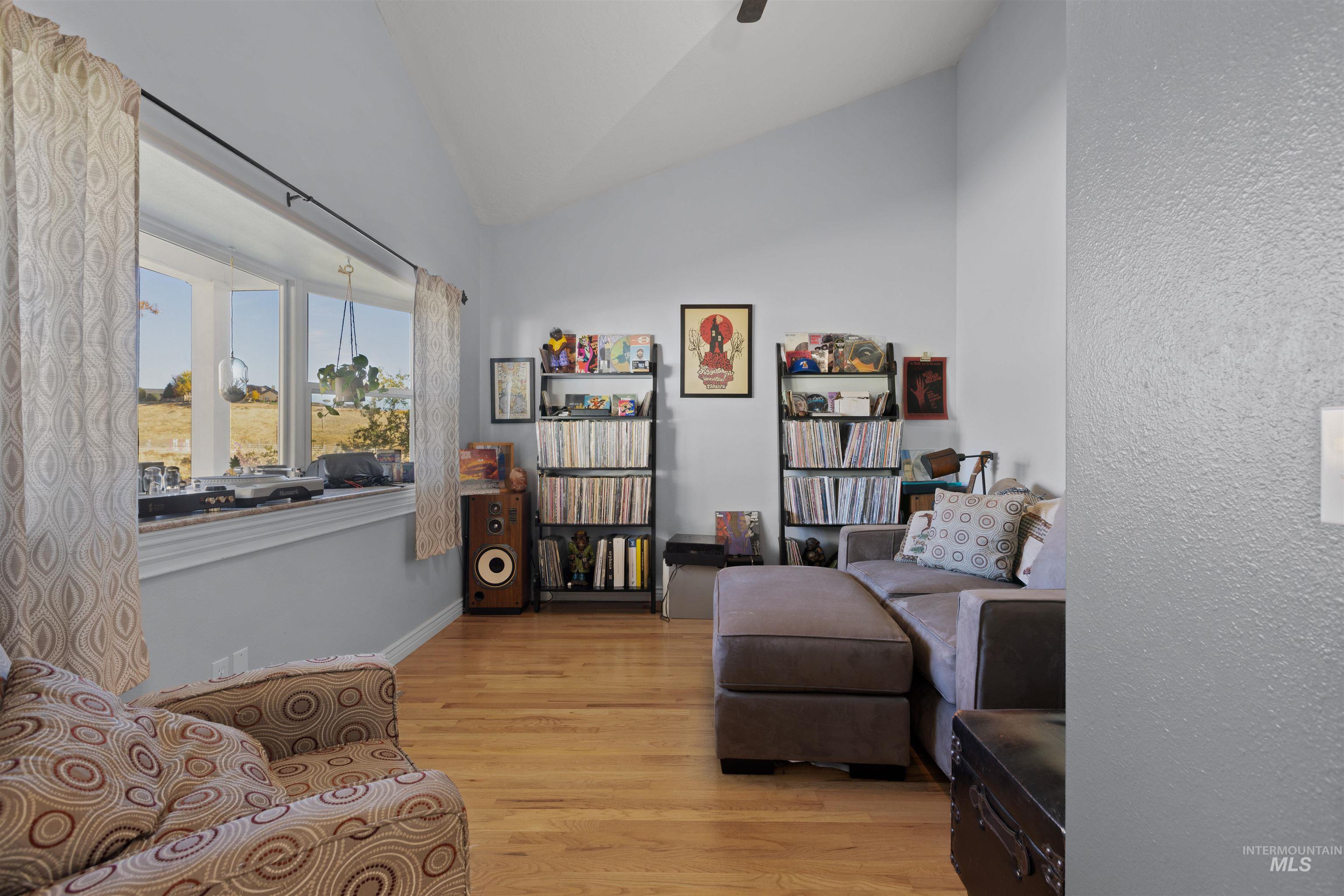 Living area featuring light wood-style floors, vaulted ceiling, and a textured wall