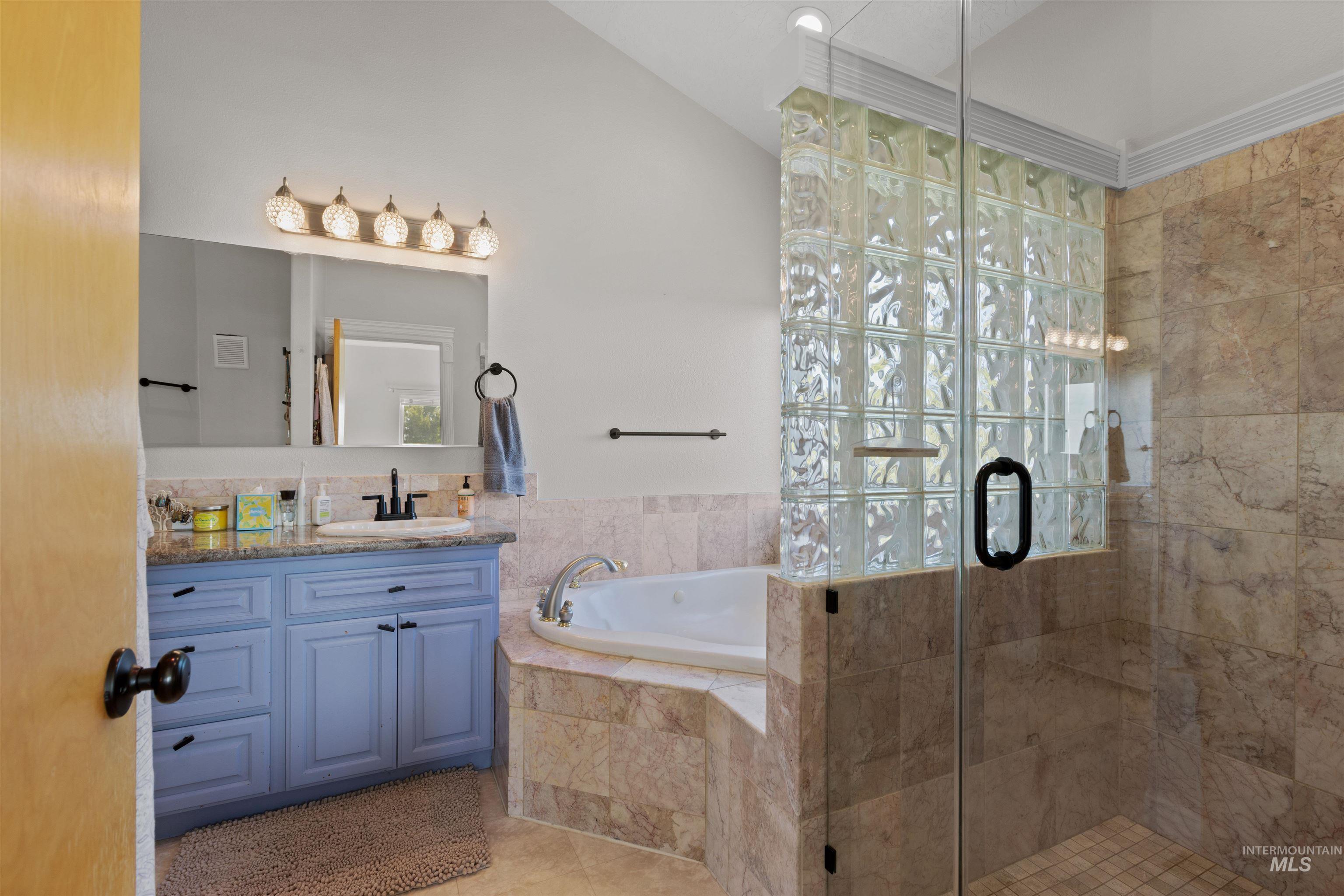 Bathroom featuring vanity, a bath, a shower stall, and light tile patterned floors