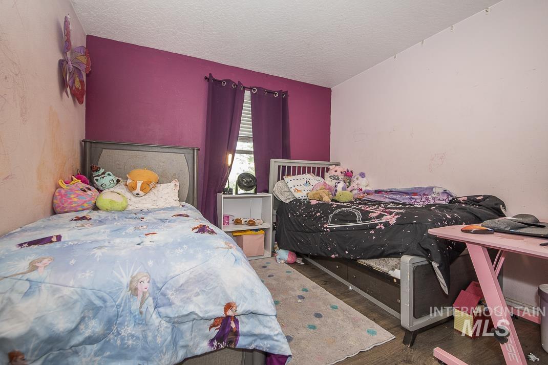 Bedroom with wood finished floors, a textured ceiling, and vaulted ceiling