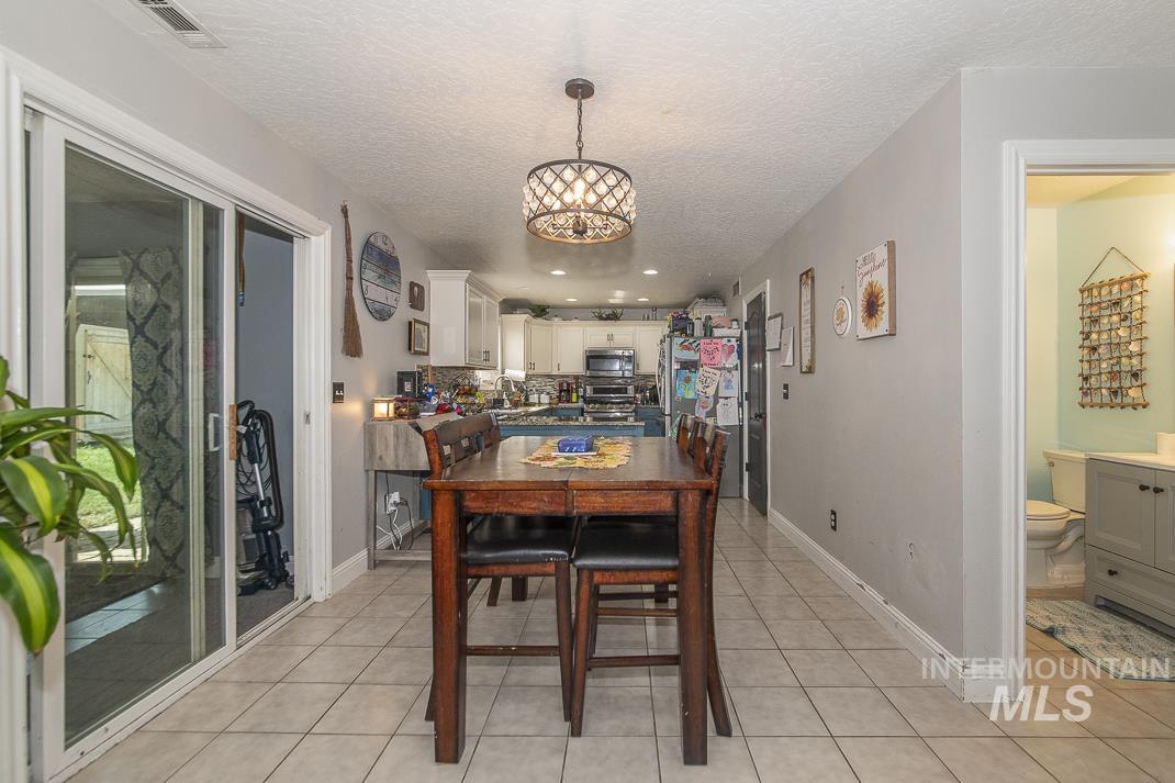 Dining area featuring light tile patterned floors, a textured ceiling, recessed lighting, and a chandelier