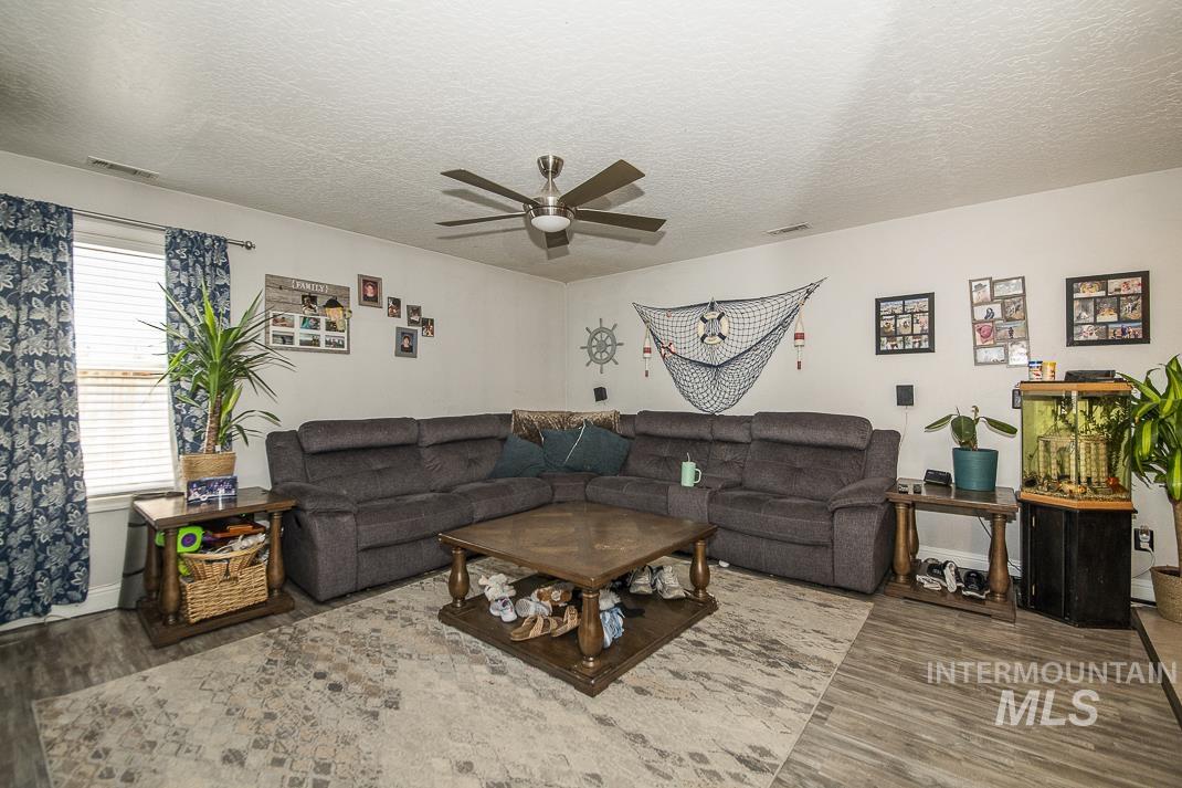 Living room with a textured ceiling, wood finished floors, and ceiling fan