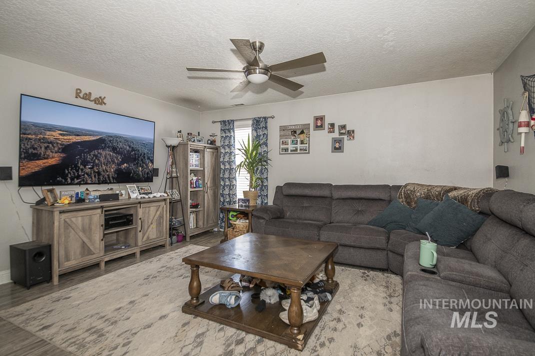 Living area featuring a textured ceiling, wood finished floors, and a ceiling fan