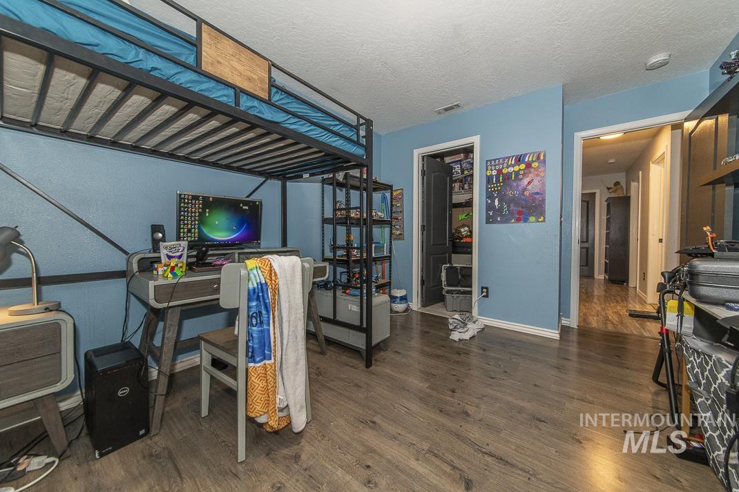 Bedroom featuring dark wood-style flooring, a textured ceiling, and black refrigerator