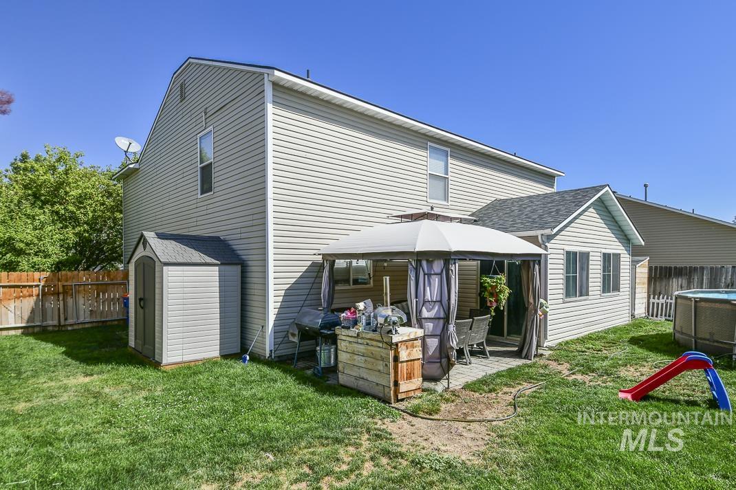 Back of property featuring a fenced backyard, a shingled roof, a storage shed, and a gazebo