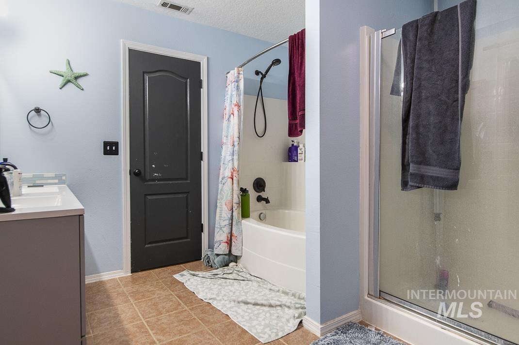 Full bathroom featuring vanity, shower / tub combo, light tile patterned floors, and a textured ceiling