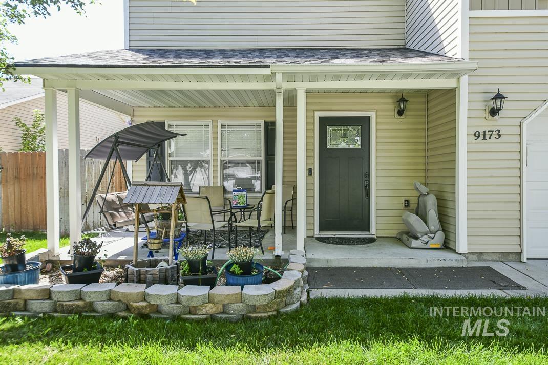 Doorway to property with a shingled roof, covered porch, and a garage