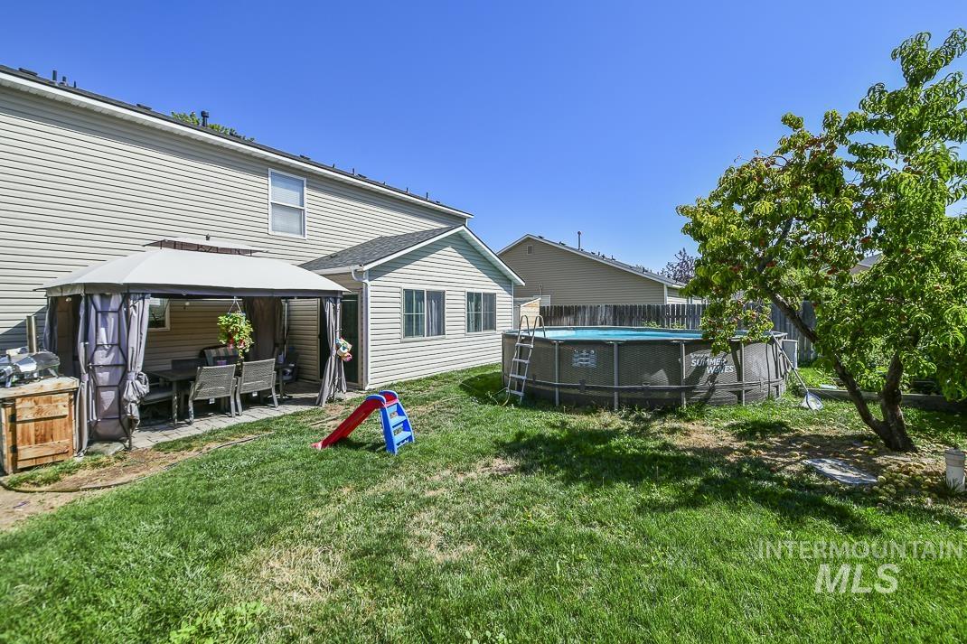 Rear view of property with a gazebo, an outdoor pool, and a patio