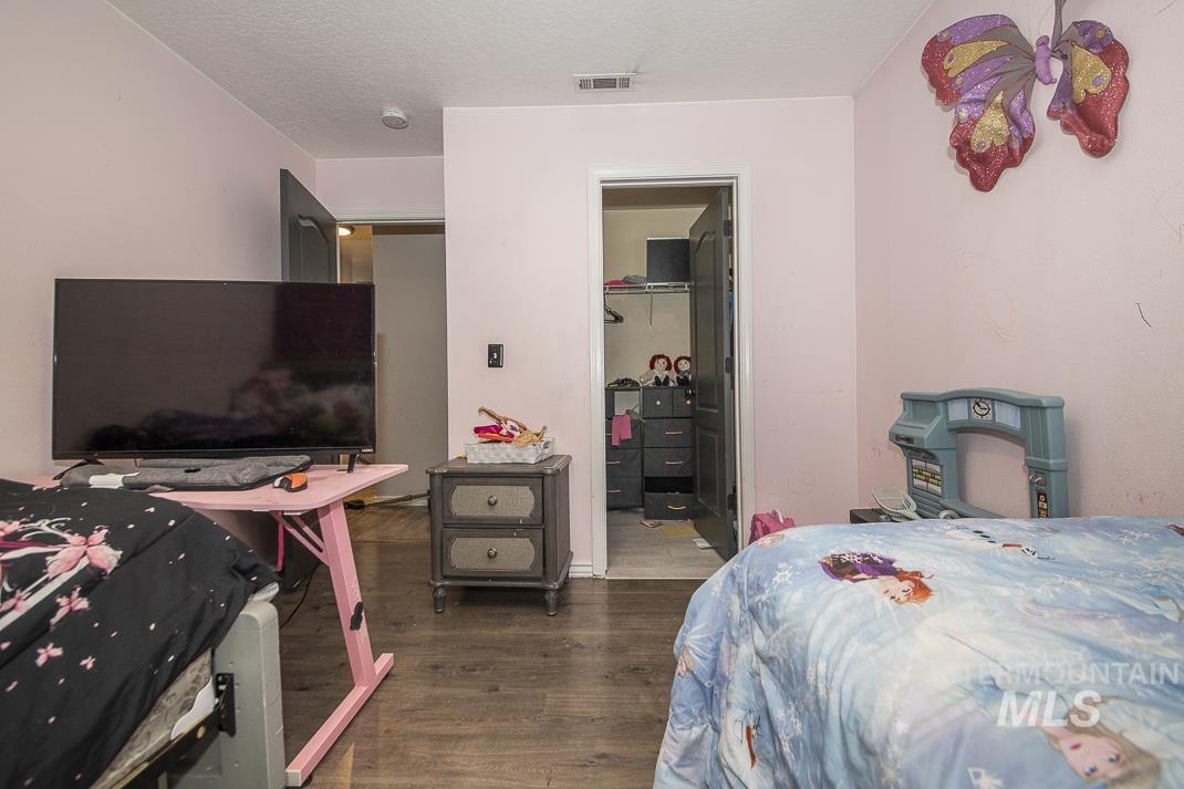 Bedroom with dark wood-style flooring, a spacious closet, and a textured ceiling