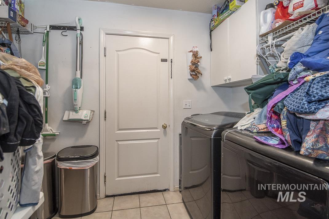 Laundry area featuring light tile patterned floors, cabinet space, and washer and clothes dryer