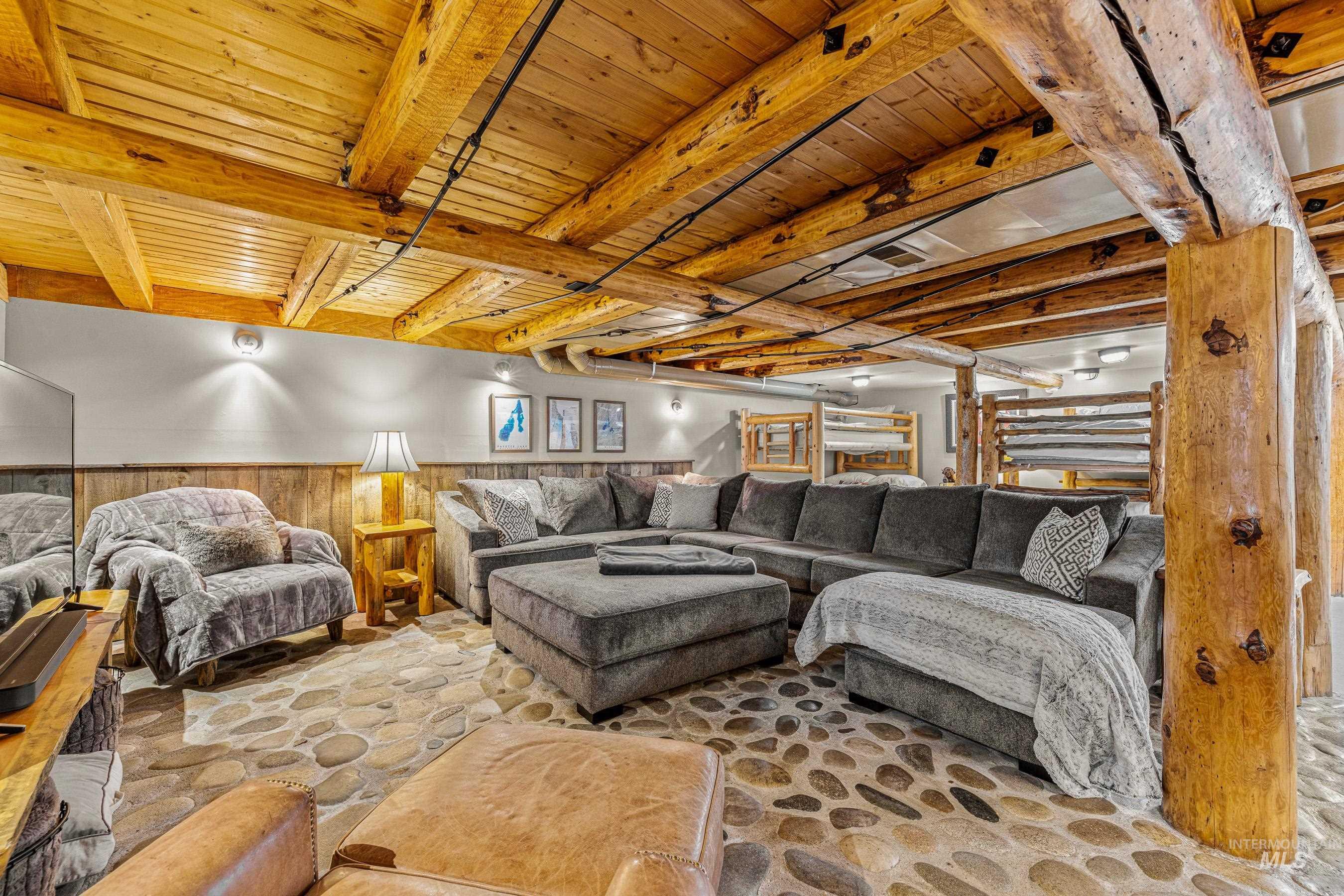 Living room with wainscoting, wood walls, and a wood ceiling with exposed beams
