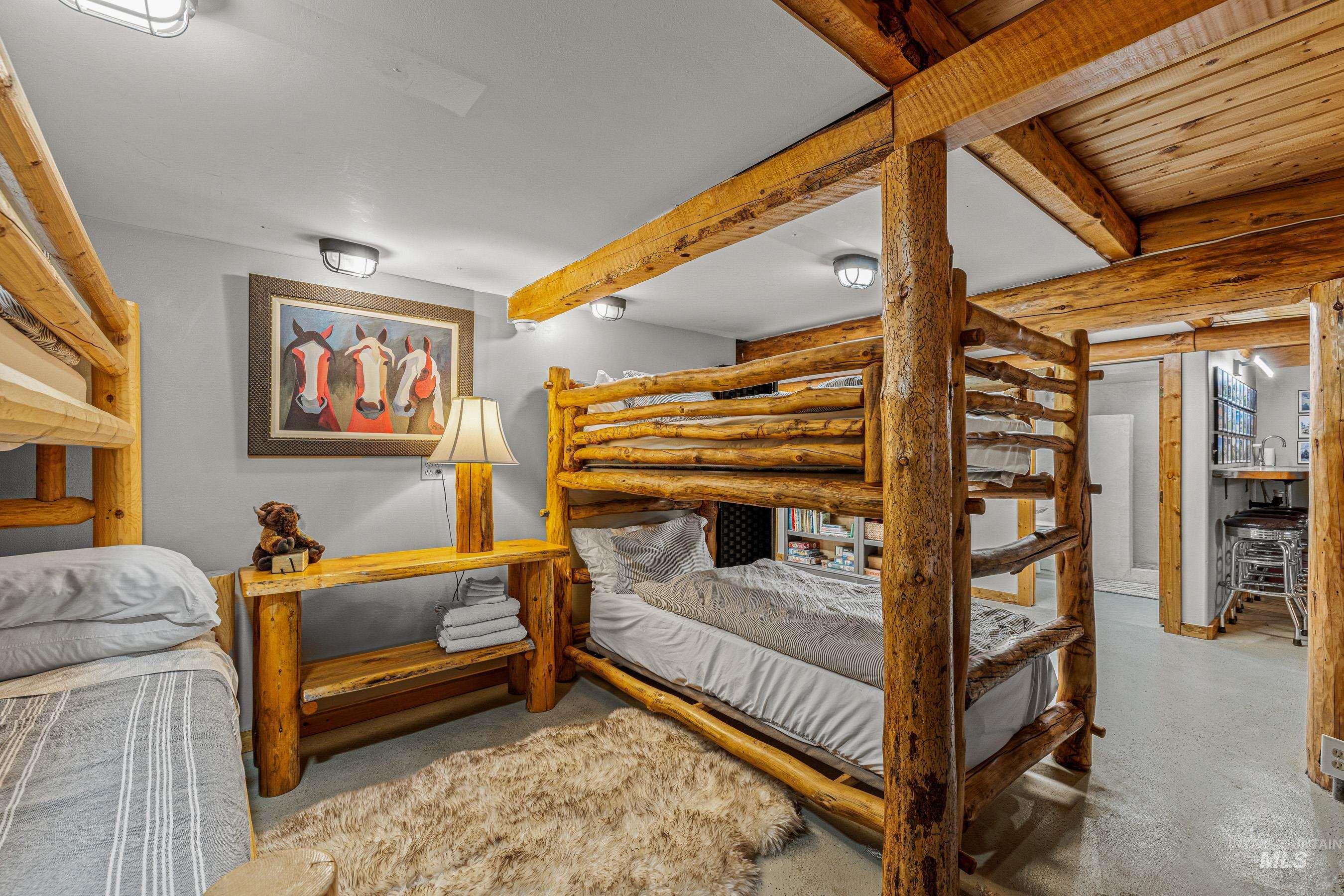 Bedroom featuring beam ceiling, finished concrete floors, and log walls