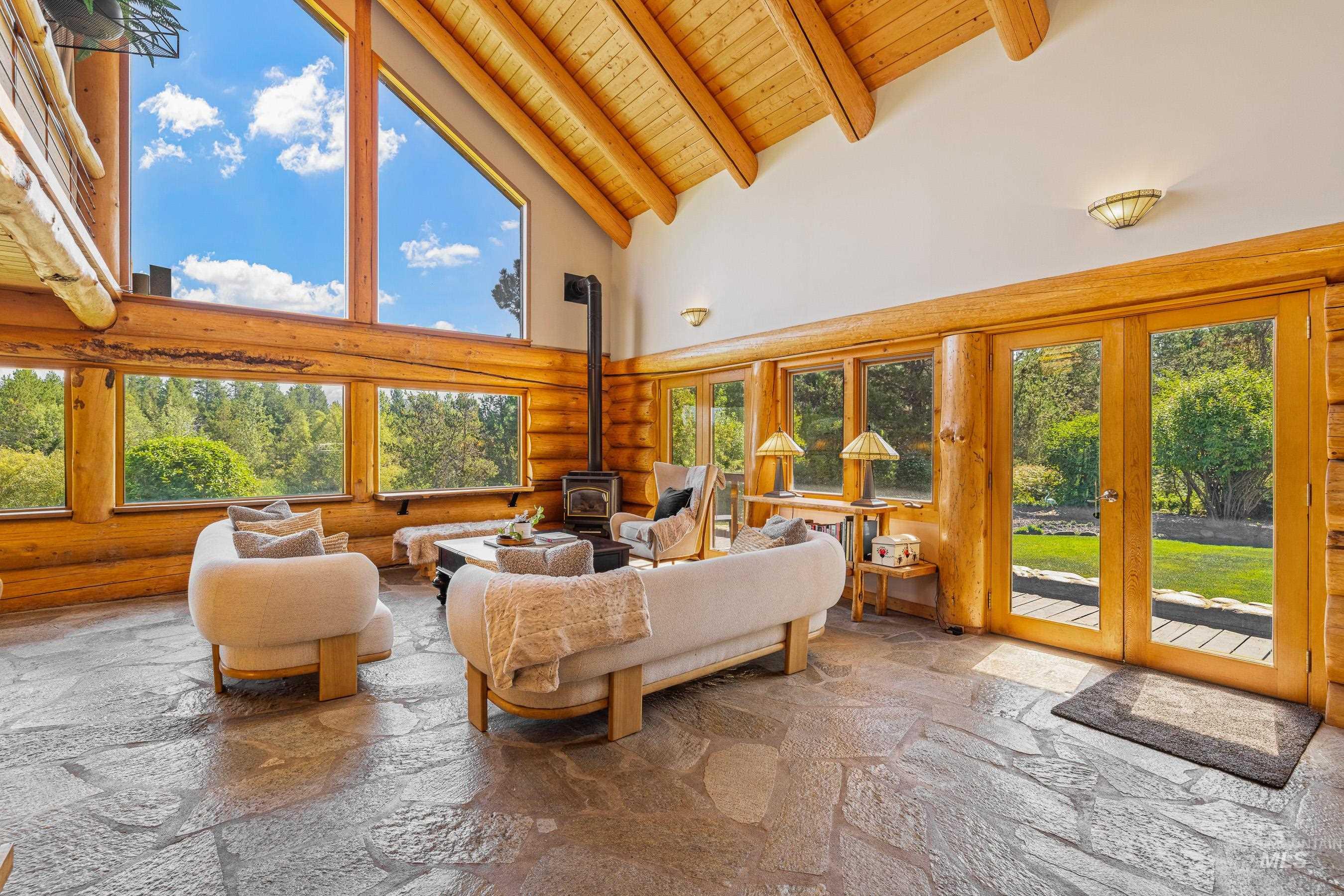 Sunroom featuring high vaulted ceiling, a wood stove, stone tile flooring, a wood ceiling with exposed beams, and french doors