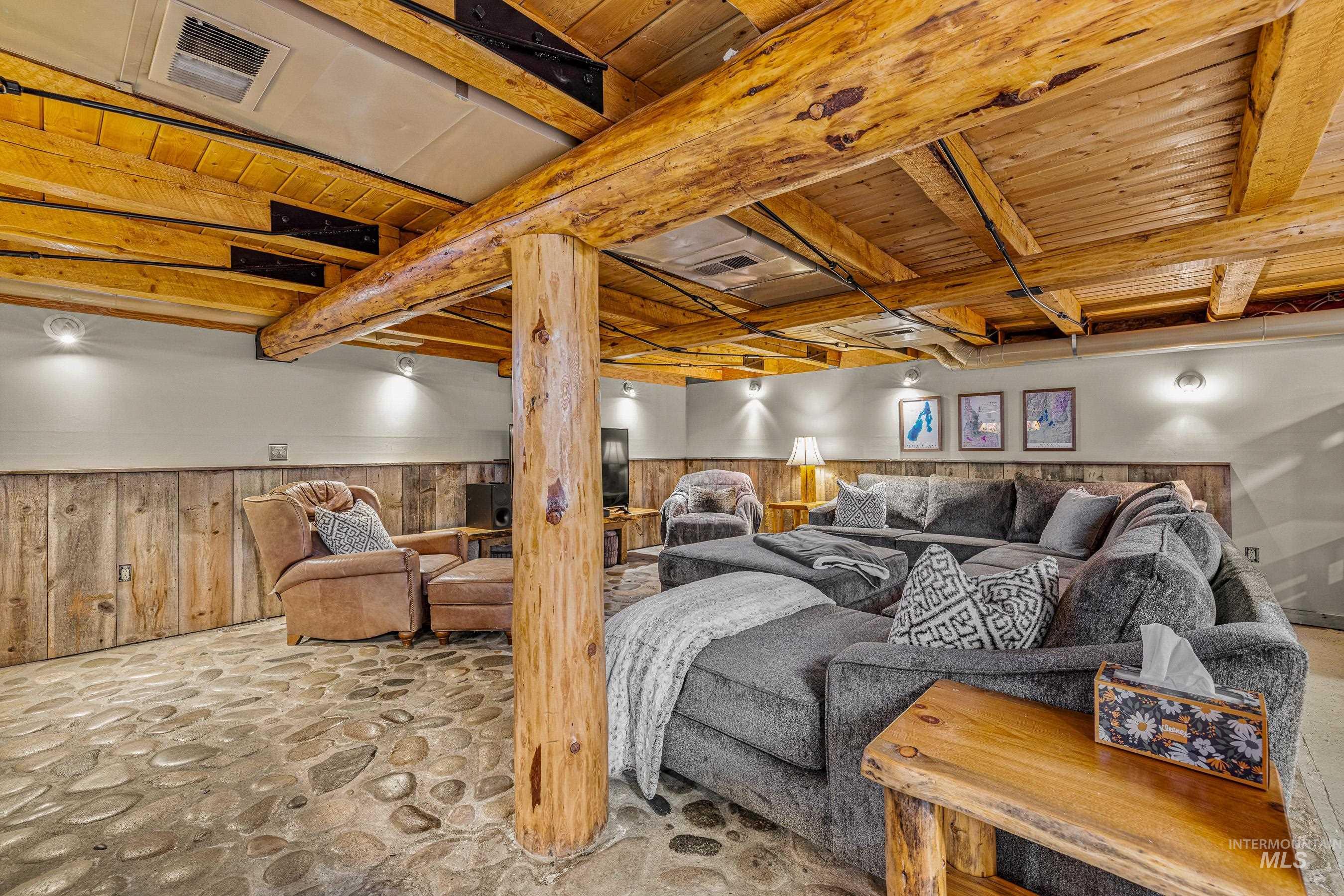 Living area with wooden walls, wainscoting, a wooden ceiling with exposed beams, and stone flooring