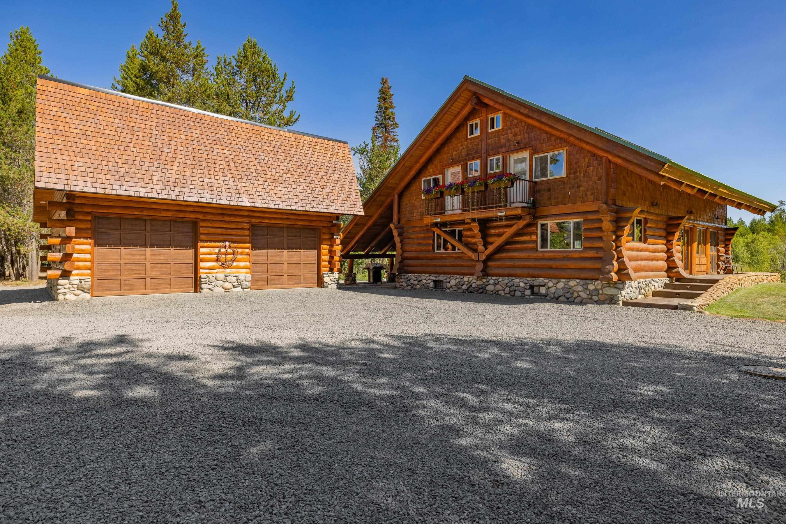 Log cabin featuring log exterior, an outdoor structure, a garage, and a deck