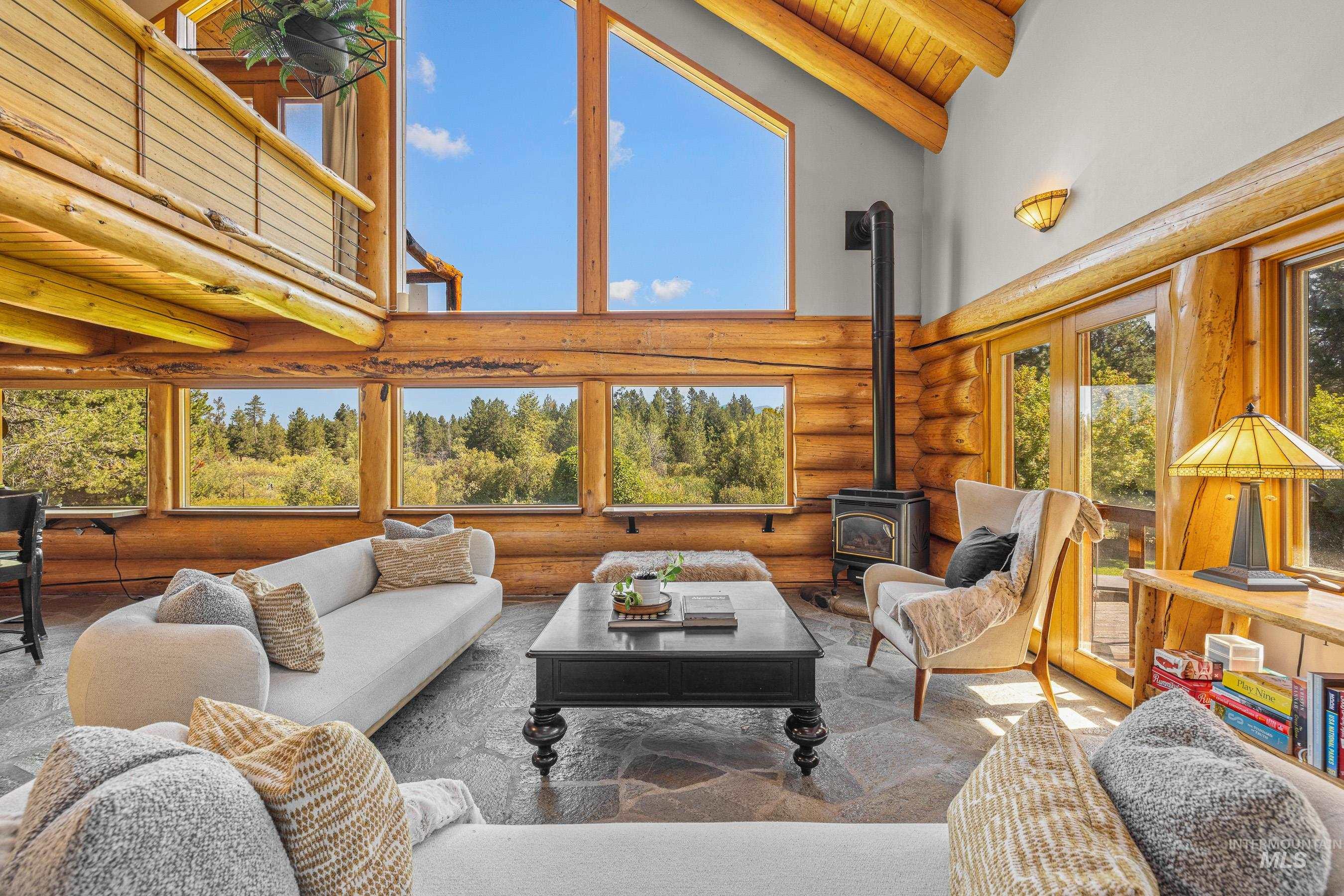 Living area featuring high vaulted ceiling, a wood stove, log walls, and a wood ceiling with exposed beams