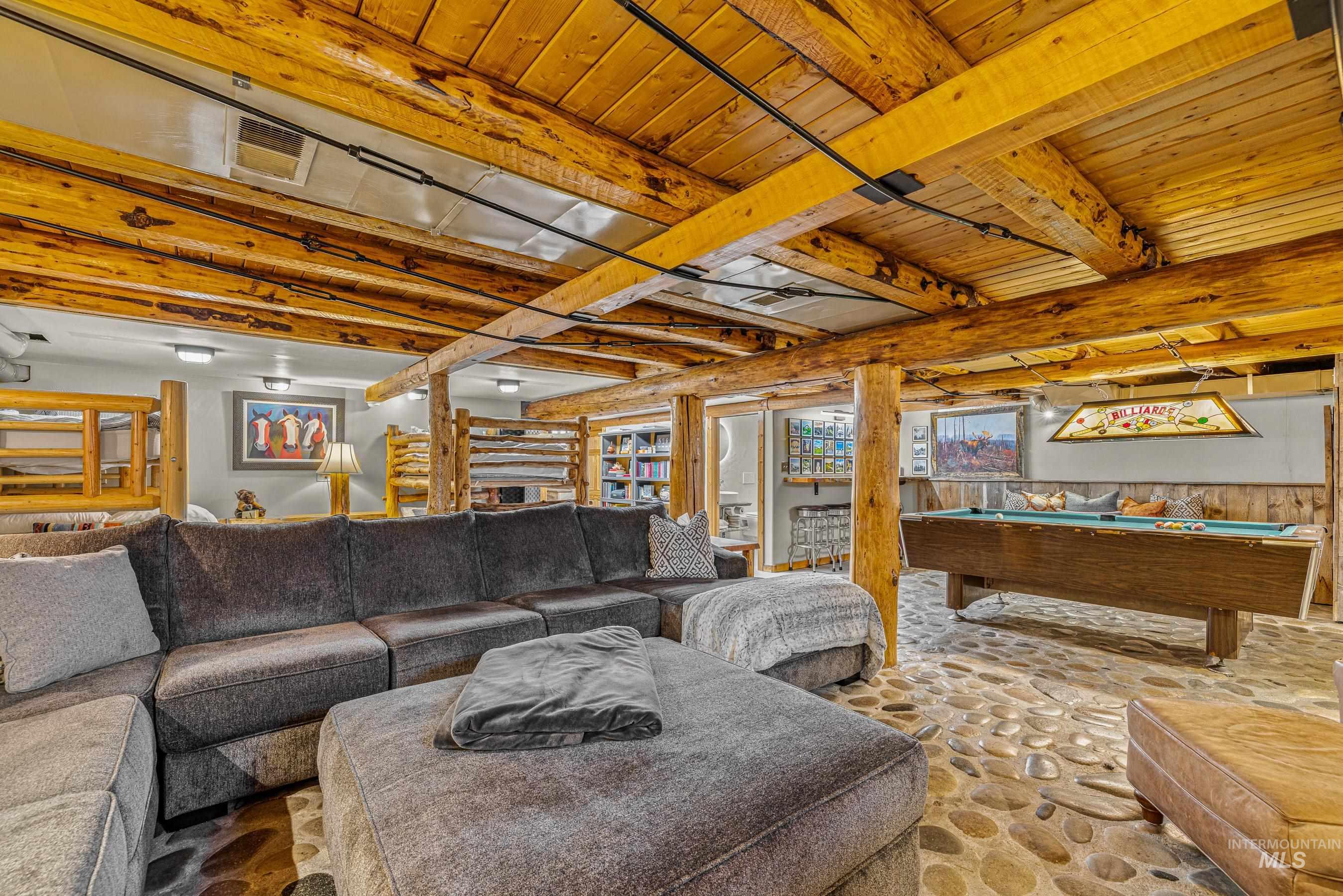 Living area featuring billiards table, a wood ceiling with exposed beams, and stone flooring