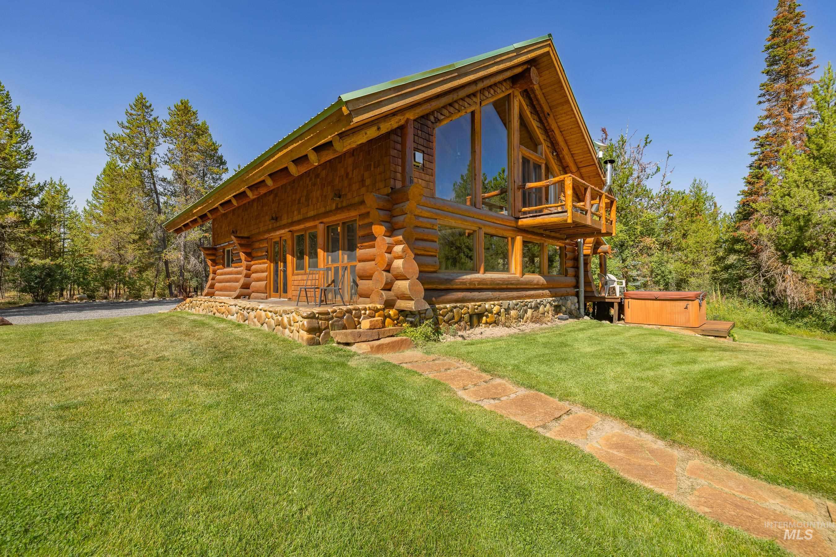 Back of house featuring a hot tub, log siding, a lawn, and a porch