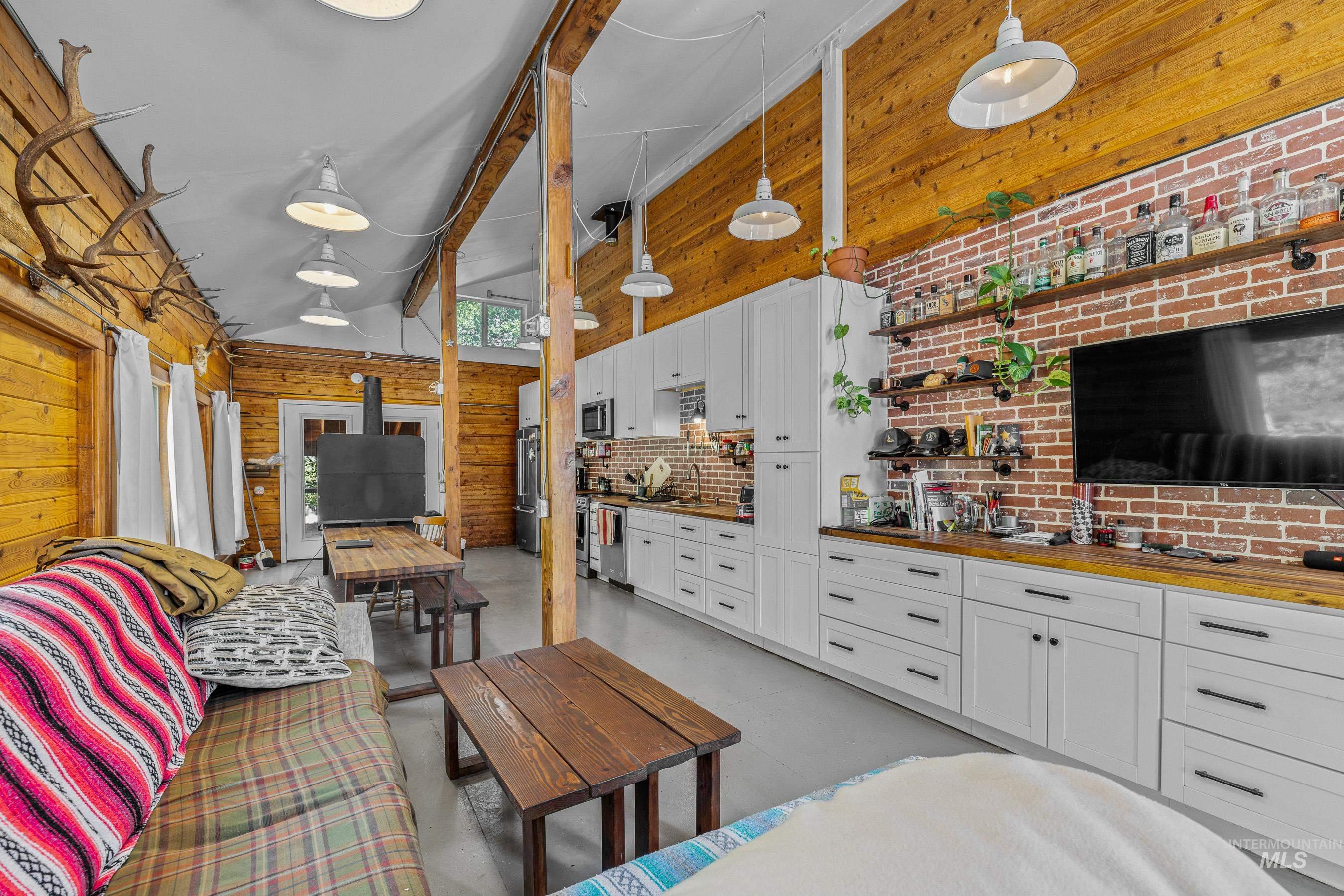 Living area with wood walls, high vaulted ceiling, and finished concrete flooring