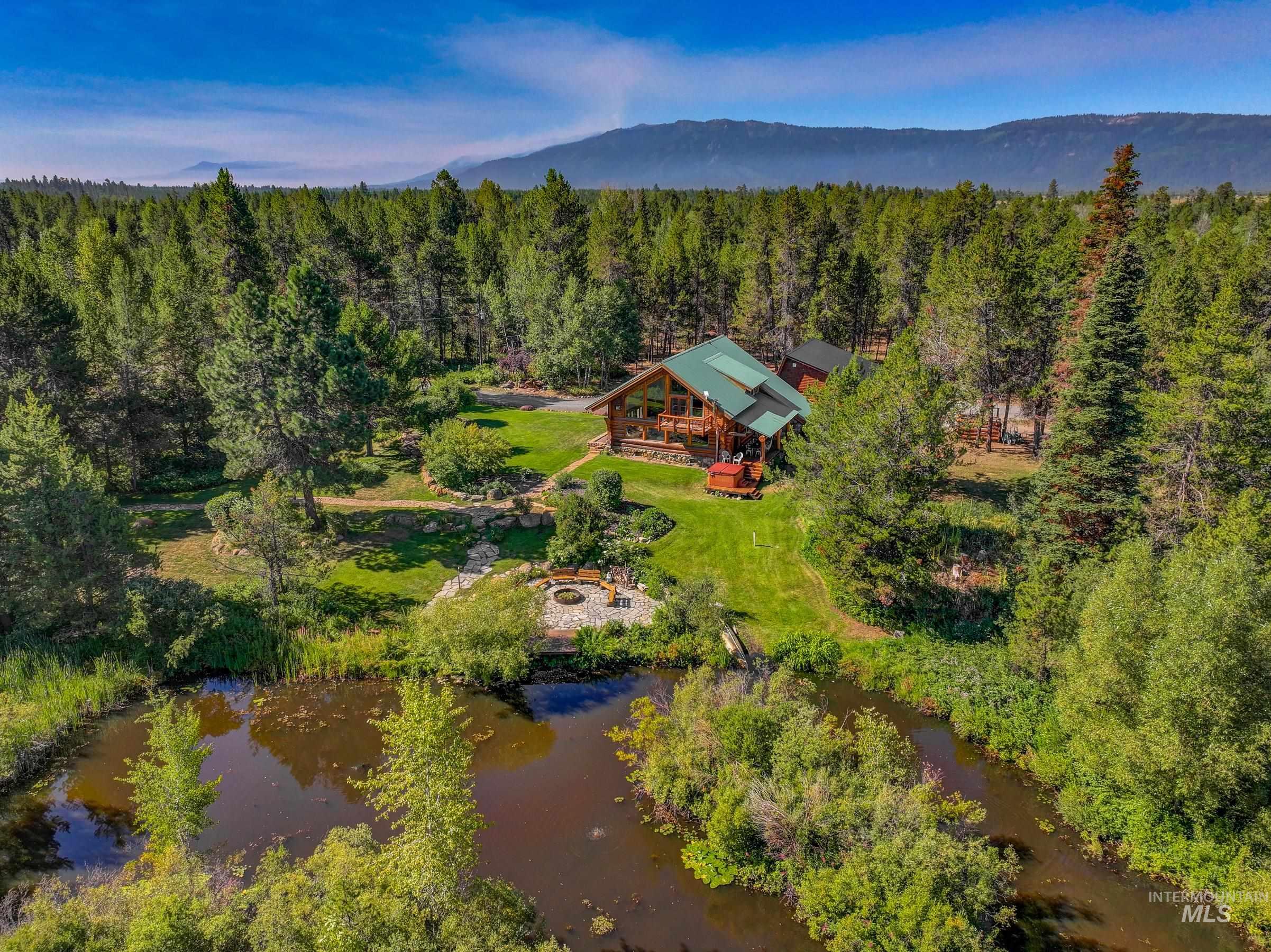 Aerial view of property and surrounding area featuring a heavily wooded area and a nearby body of water