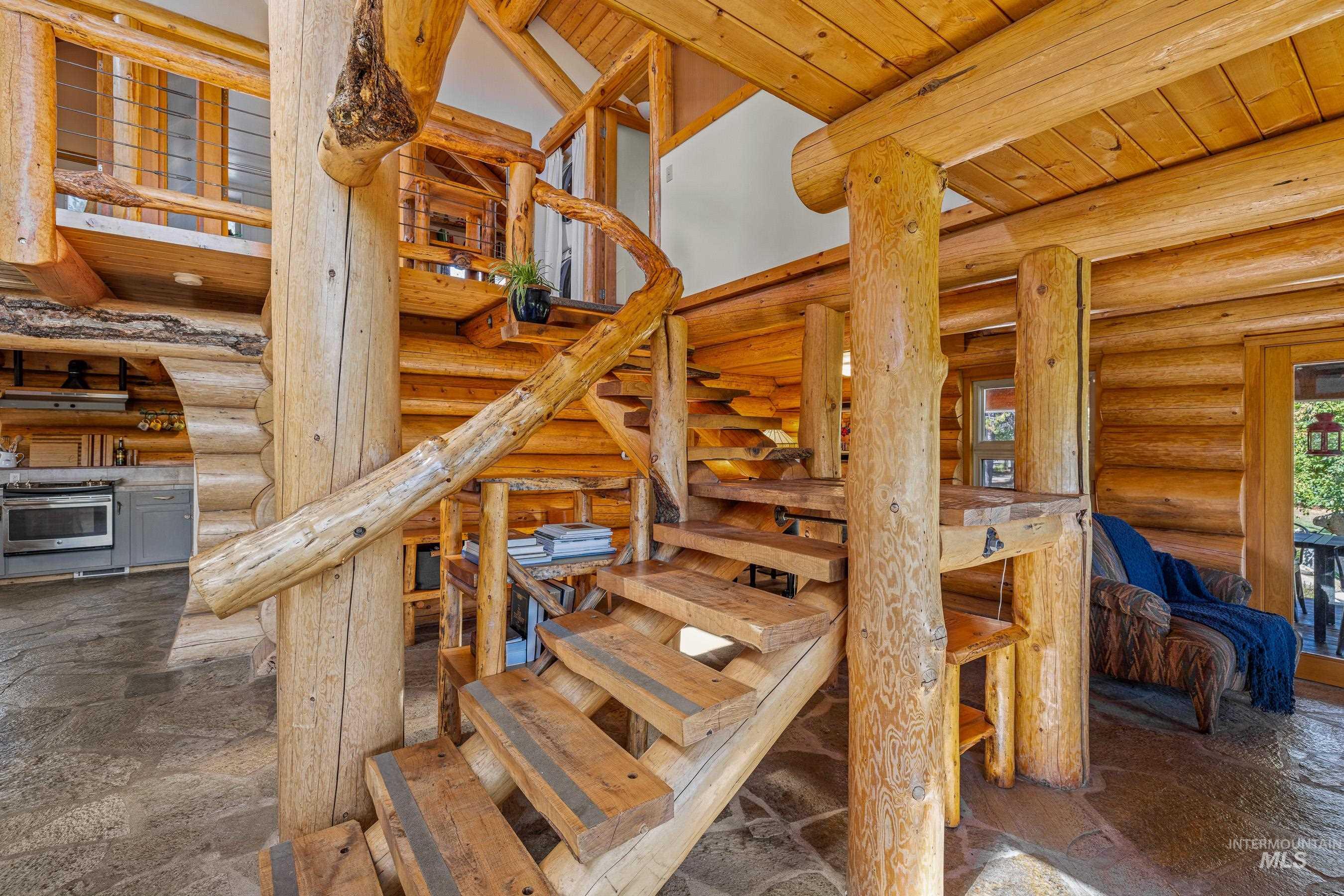 Stairs with rustic walls, a wooden ceiling with exposed beams, stone finish flooring, and a towering ceiling