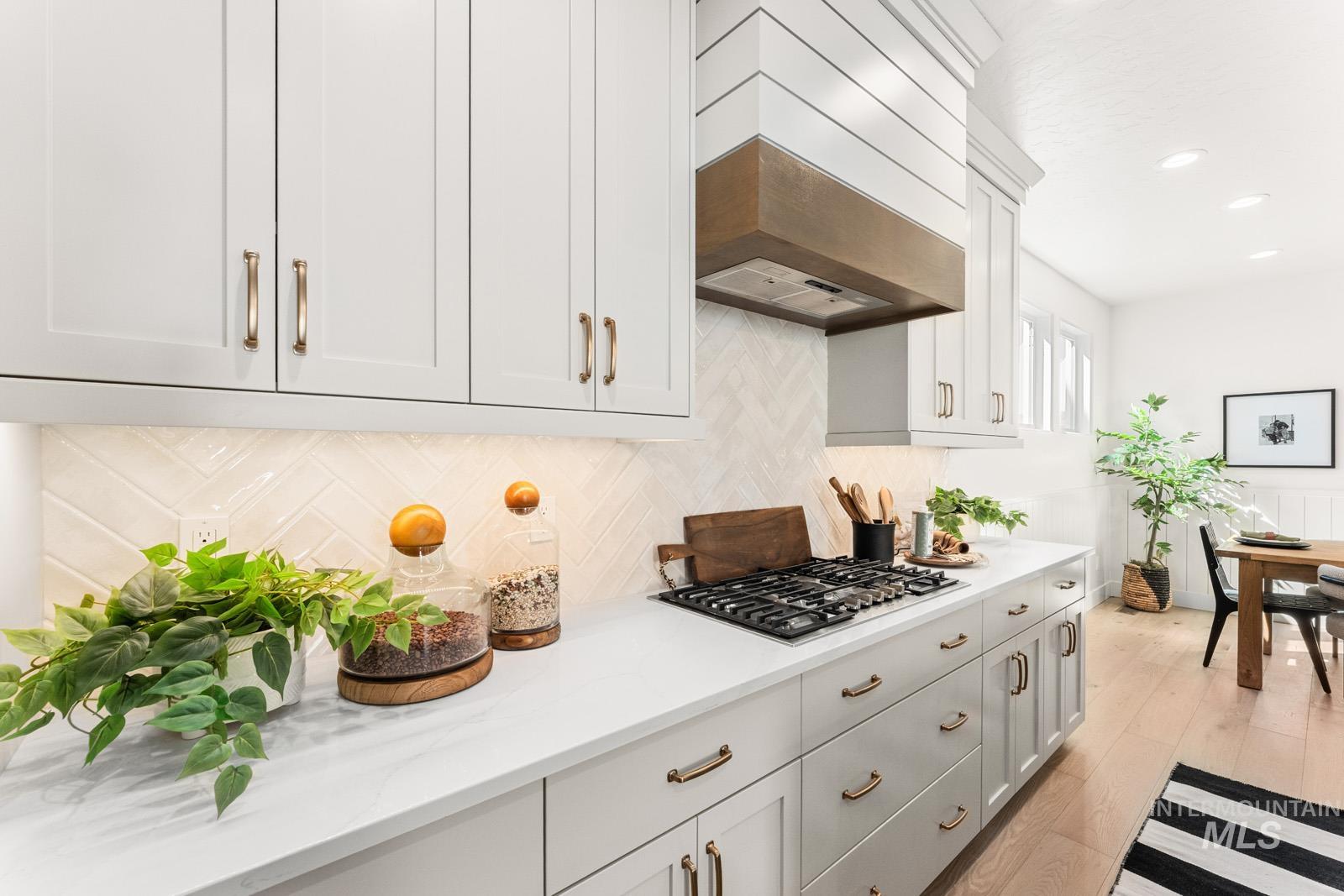 Kitchen with light wood-style flooring, light stone countertops, stainless steel gas cooktop, recessed lighting, and white cabinetry