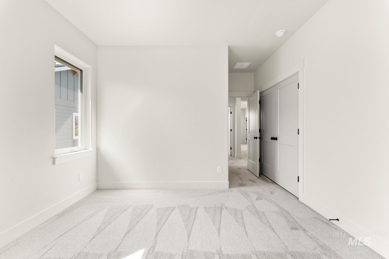 Empty room with light colored carpet and baseboards