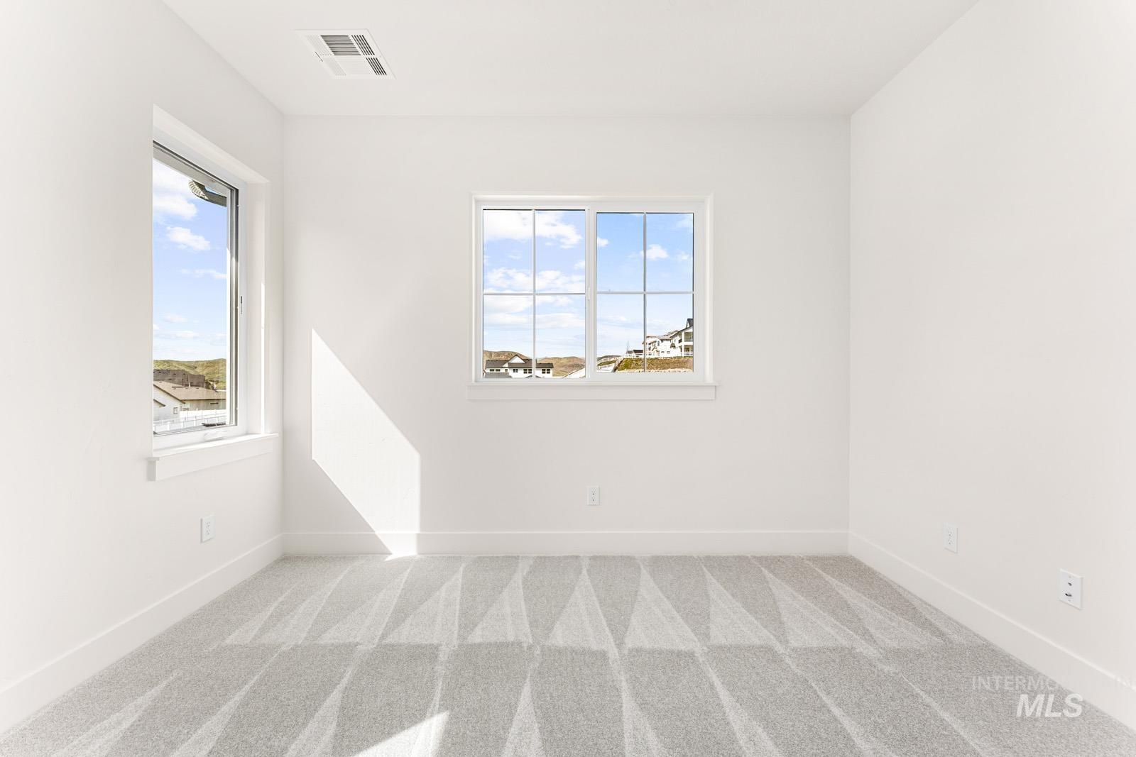 Spare room with light colored carpet and baseboards