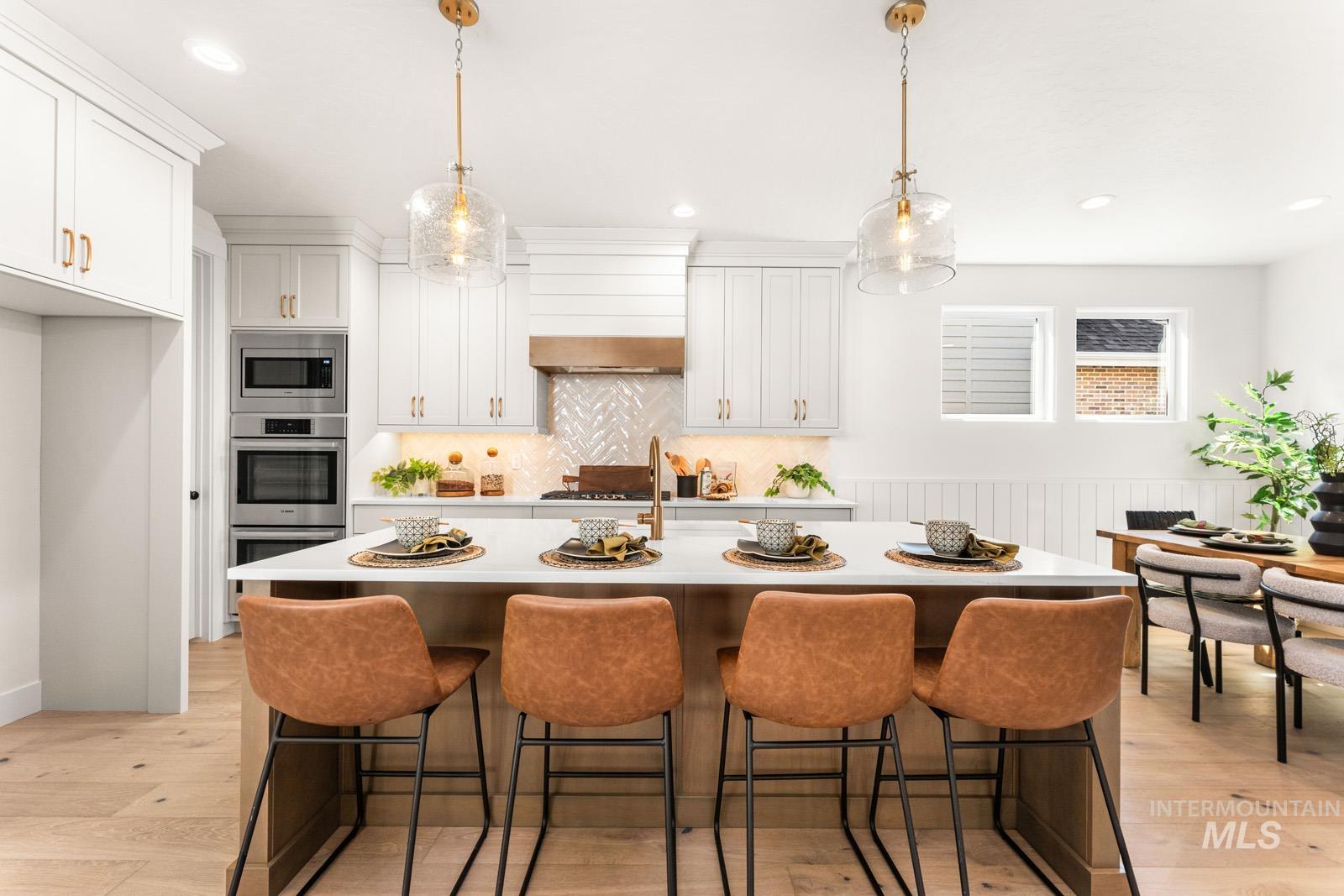 Kitchen featuring a breakfast bar, decorative light fixtures, stainless steel appliances, and a wainscoted wall