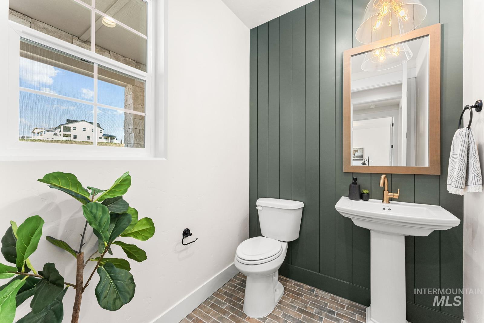 Half bath with brick patterned flooring and wood walls