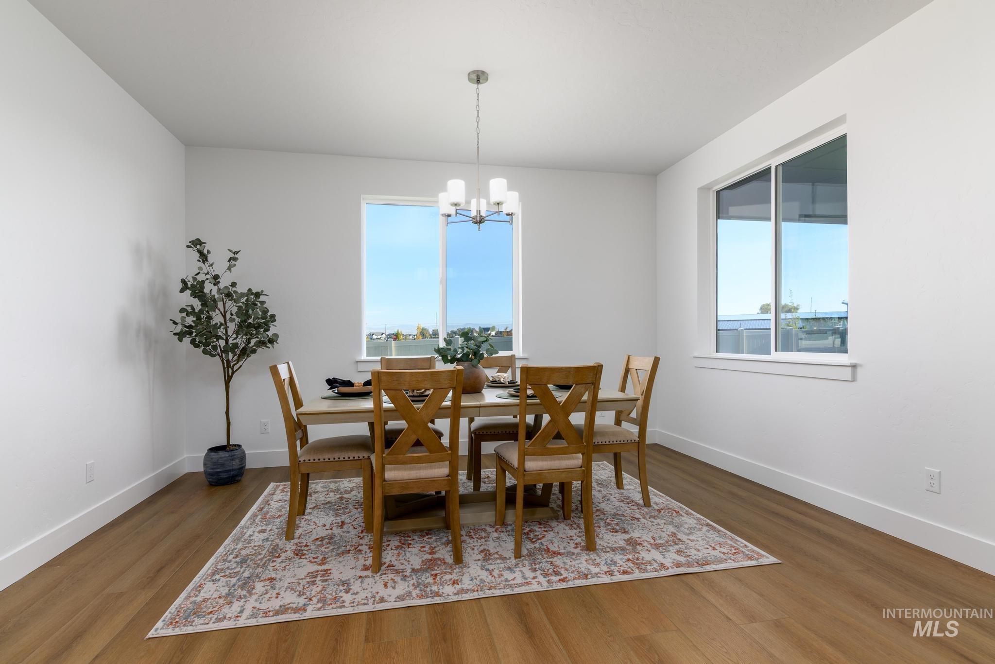 Dining area with dark wood-style flooring, plenty of natural light, and a chandelier
