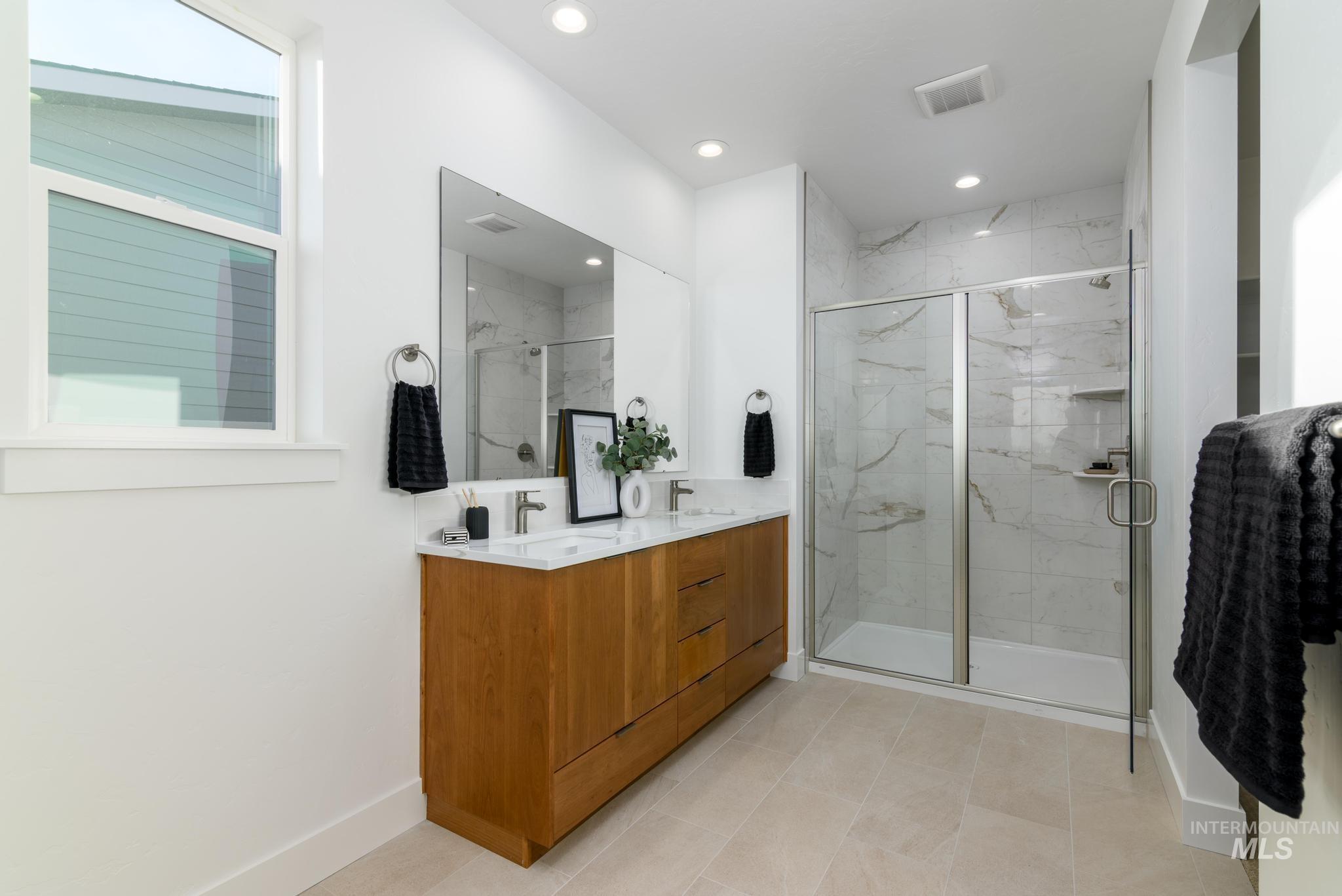 Full bath with double vanity, a marble finish shower, and recessed lighting