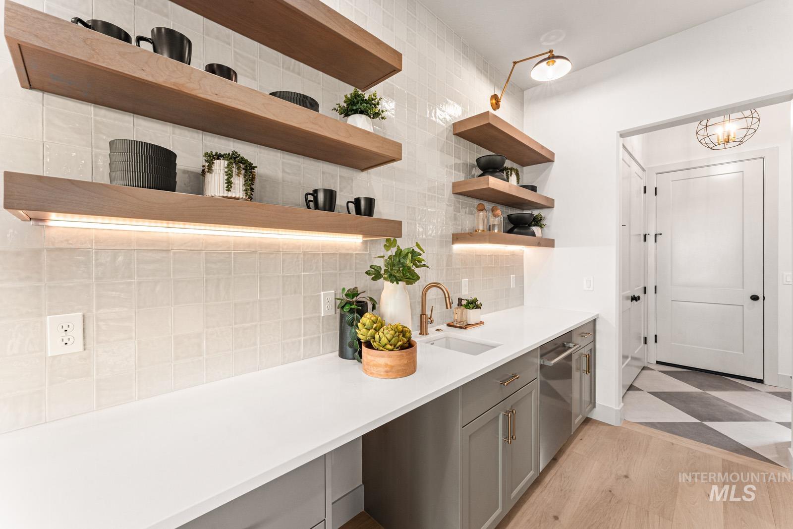 Bar with decorative backsplash, gray cabinetry, light stone countertops, stainless steel dishwasher, and light wood-type flooring